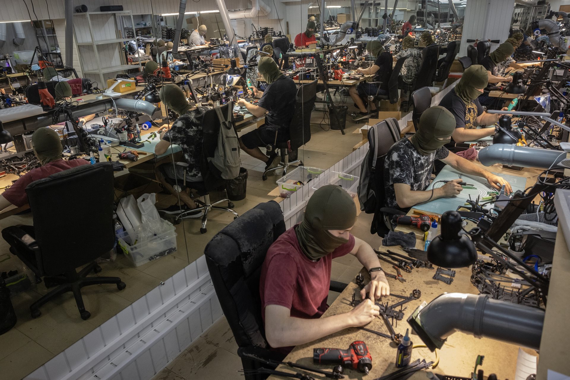 Ukrainian civilians, their identities concealed behind masks, assemble FPV drones in a basement factory. Both Ukraine and Russia now manufacture millions of battlefield drones a year. Central Ukraine