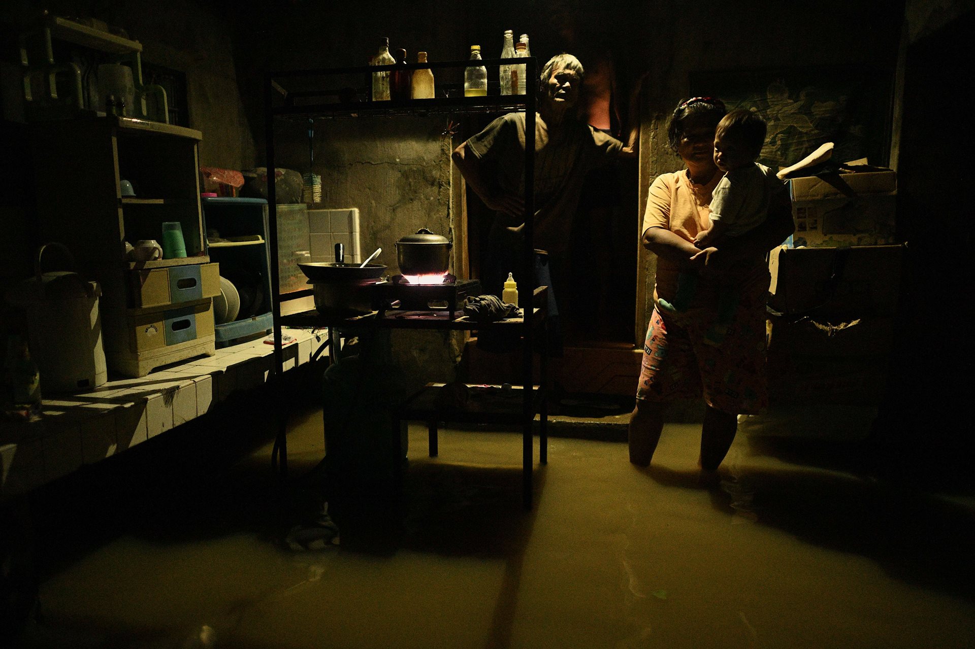 A family stands in their flooded home in Buguey, Cagayan, northern Philippines, following Typhoon Yinxing. More than 40,000 villagers in Cagayan province were evacuated to safer grounds.&nbsp;