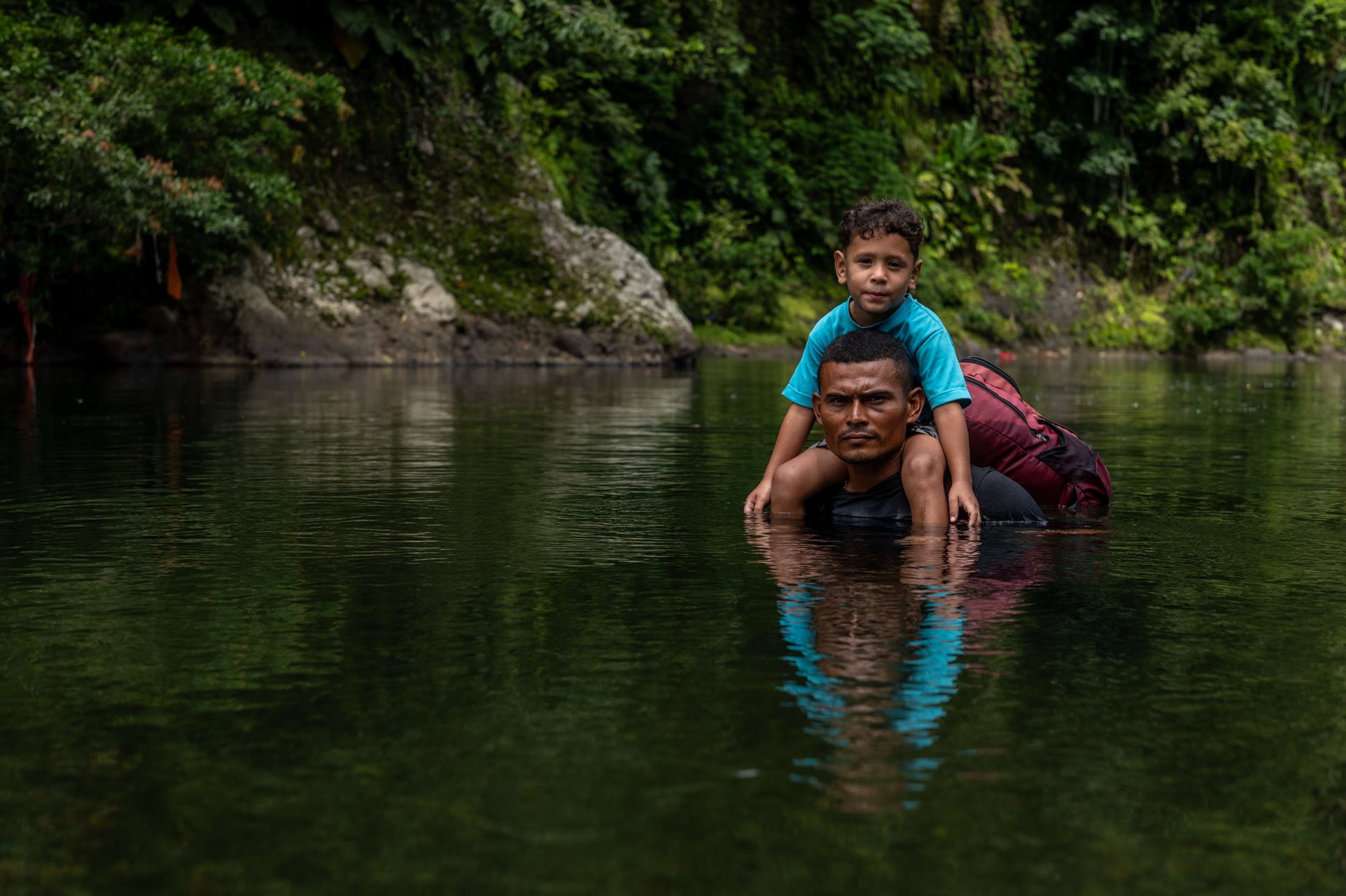 Jonathan Franco crosses a deep river with four-year-old Keyner de Jesús. Franco was nicknamed &quot;Rambo.&quot; His physical strength allowed him to help other families by carrying their children during the most challenging sections of the journey through the Darién Gap.&nbsp;
