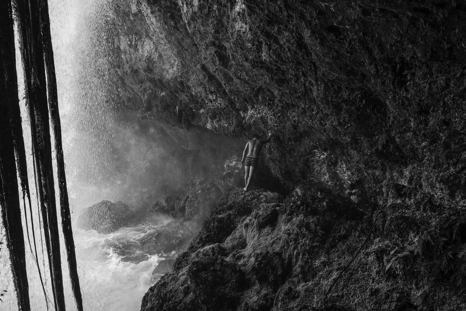 <p>Mailon Araxi, a young member of the Manoki Indigenous community, crosses the Cravari River under a waterfall in the Irantxe Indigenous Land, in Mato Grosso, Brazil. Stalled in the process of trying to recover their traditional land rights, many Manoki have turned to work in large commercial soybean farms for income.</p>
