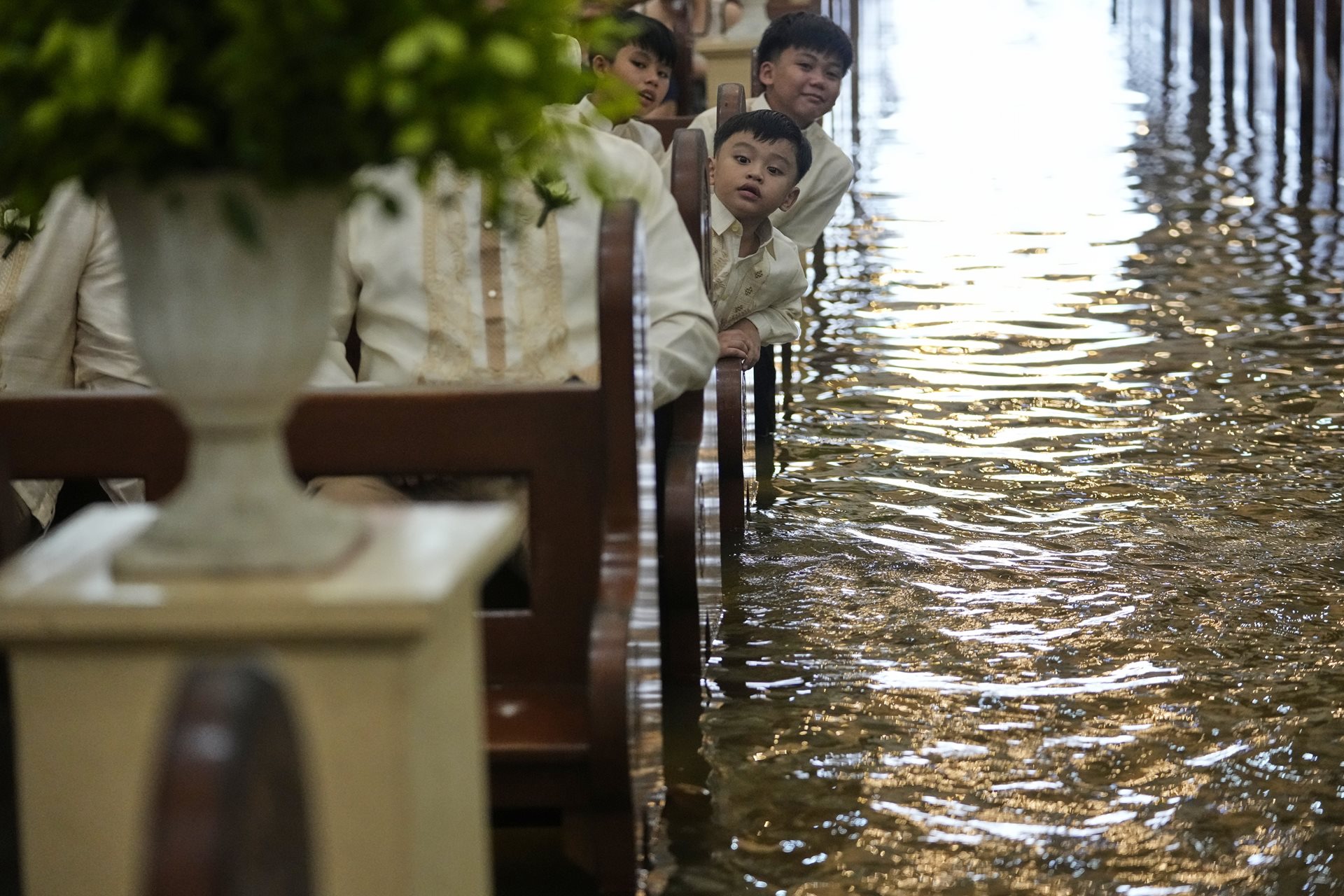 Inside the church, young guests look on attentively. The intensity of tropical cyclones and associated rainfall that has hit the Philippines has significantly increased since 2012. Malolos, Bulacan province, Philippines.