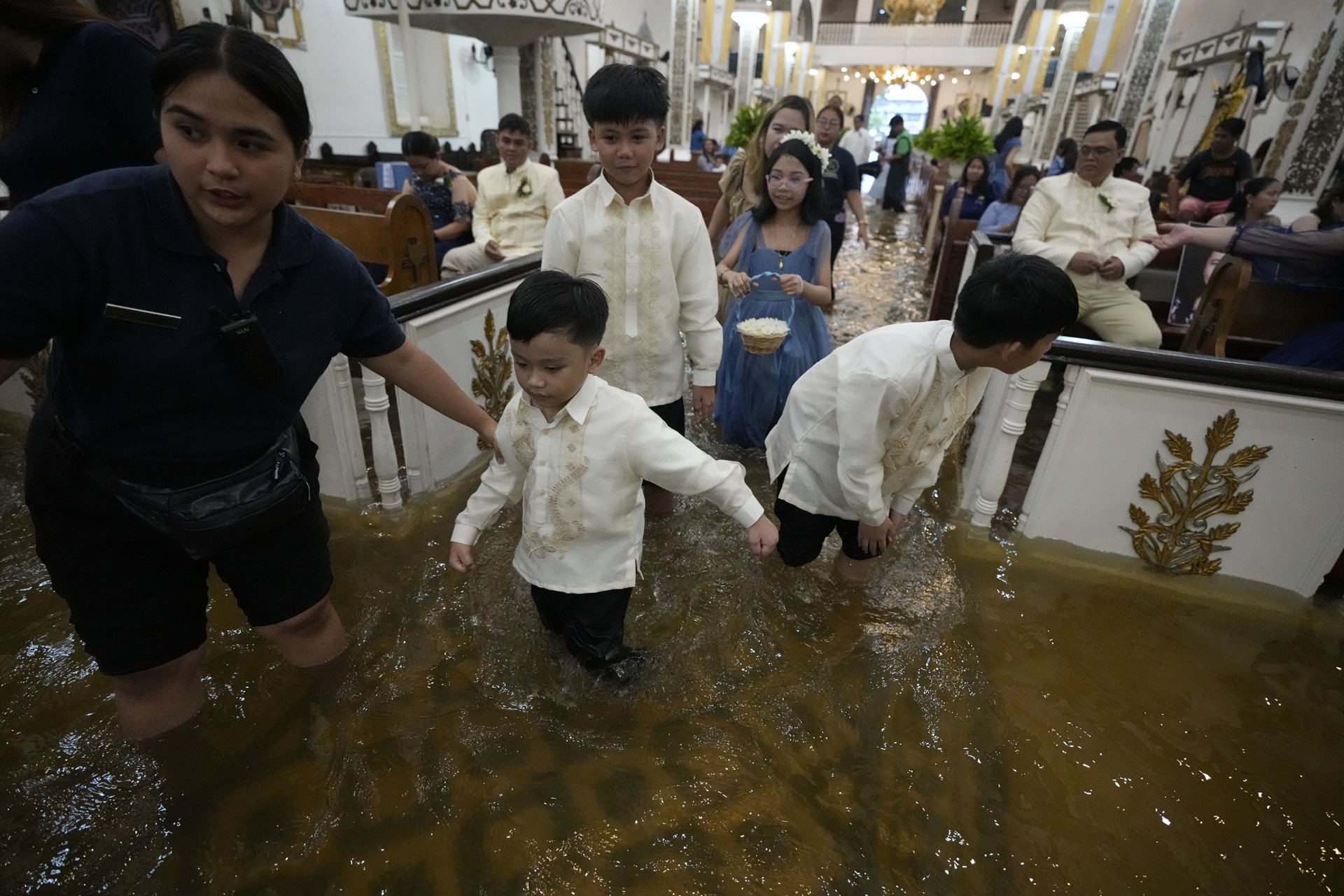 Wedding guests walk inside the flooded nave of the Barasoain Church in Malolos, Bulacan province, Philippines. The photographer reached the ceremony on a passing rescue truck after deep water rendered local roads impassable for his car.