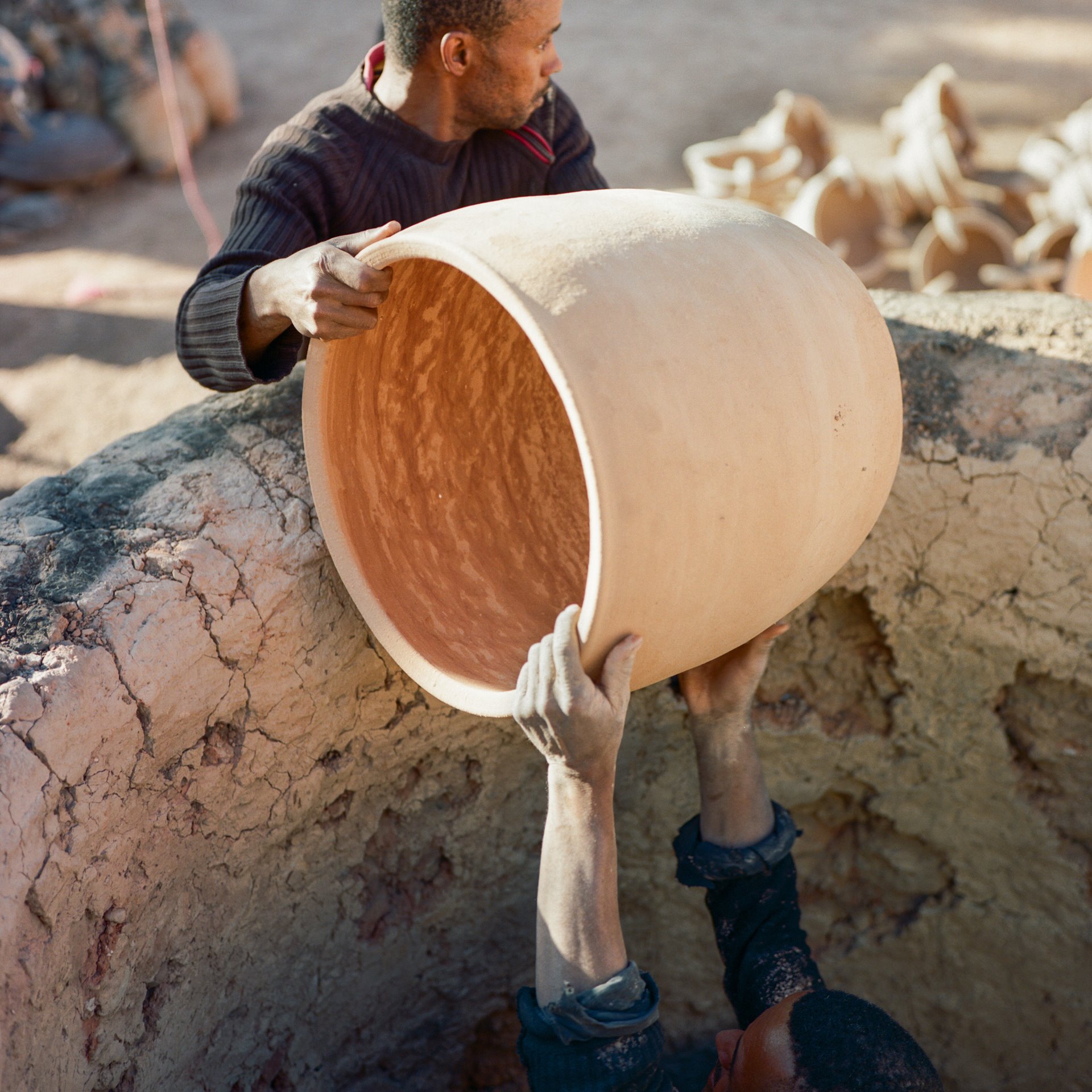 Aziz Elfakhar (left) hands a pot to his brother Mohammed to place in their kiln for firing, at the Skoura Oasis, in central Morocco. Mohammed says that when crops are poor, fewer people come to barter produce for pots. He prefers bartering as a way of doing business, as it means he does not have to go to the trouble and expense of transporting all his goods to a souk on market days, and waiting until he has sold them before he can buy food.