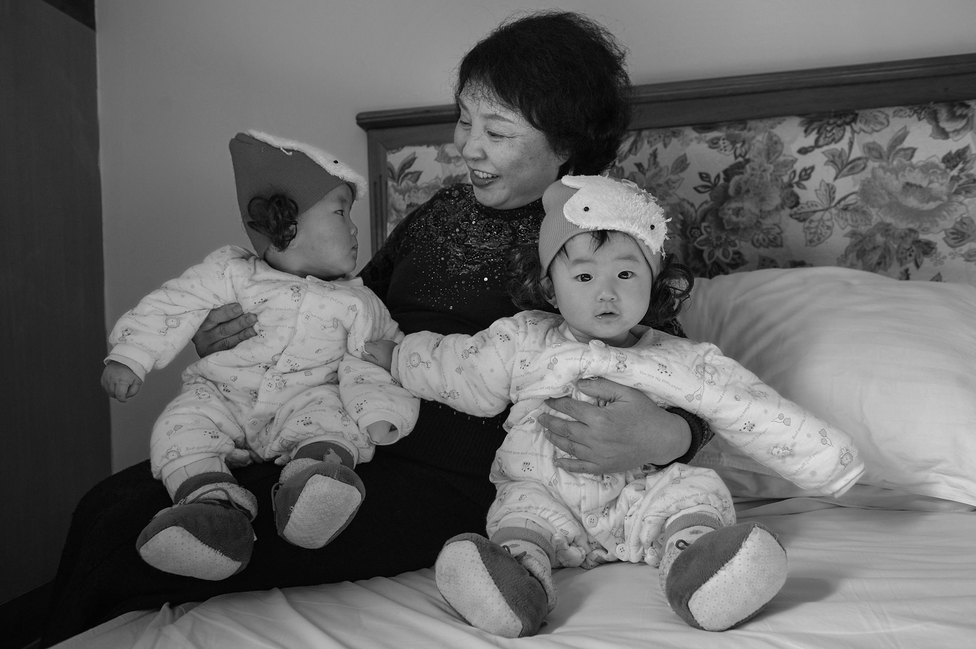 Sheng Hailin at home with Zhizhi and Huihui in Hefei, Anhui Province, China. The twins are wearing new hats purchased for their first Spring Festival.&nbsp;