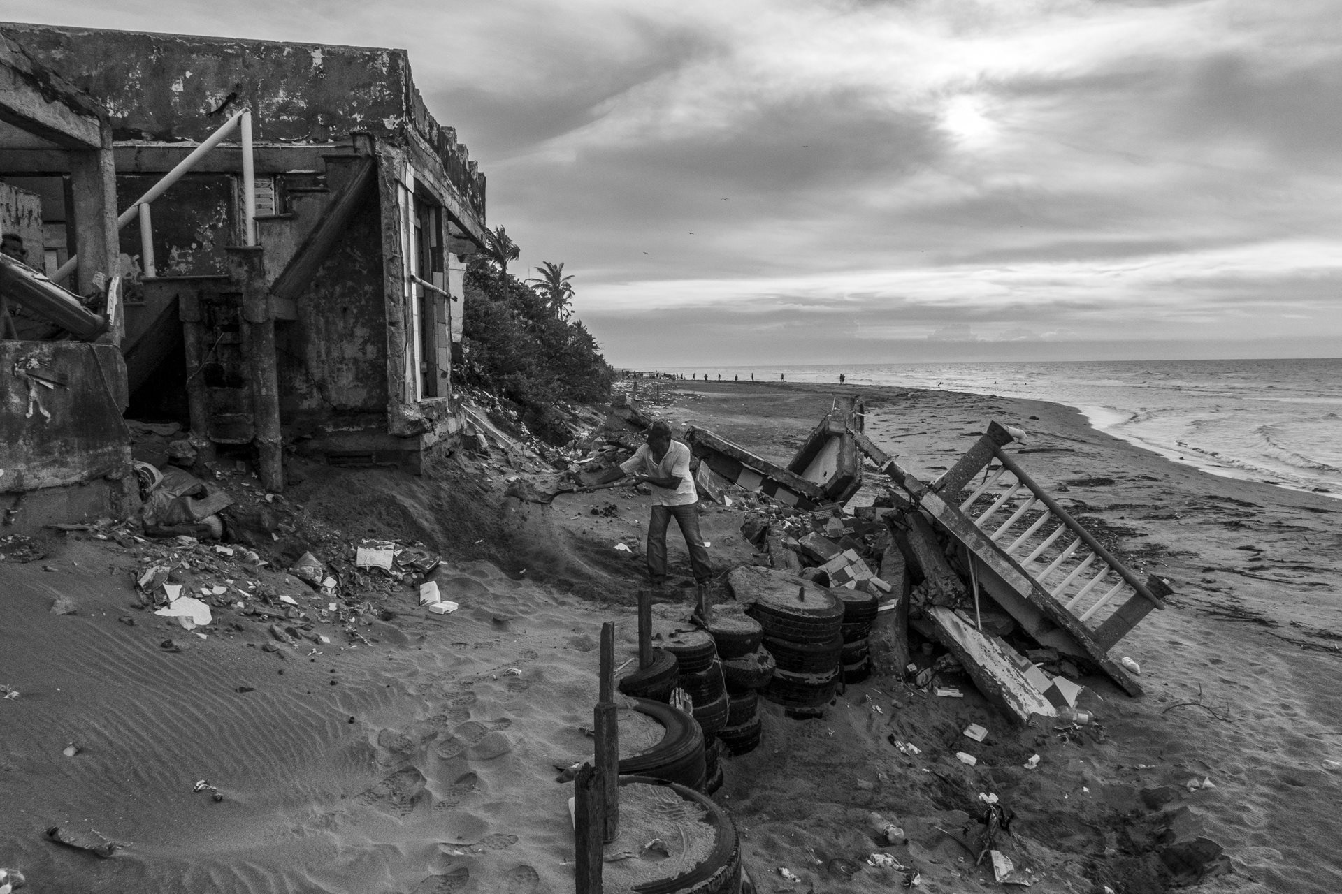 <p>Juan Izquierdo shovels sand to shore up his home&rsquo;s foundation. Seven days after this photograph was taken, another section of the house collapsed. Sánchez Magallanes, Tabasco, Mexico</p>
<br />
&nbsp;