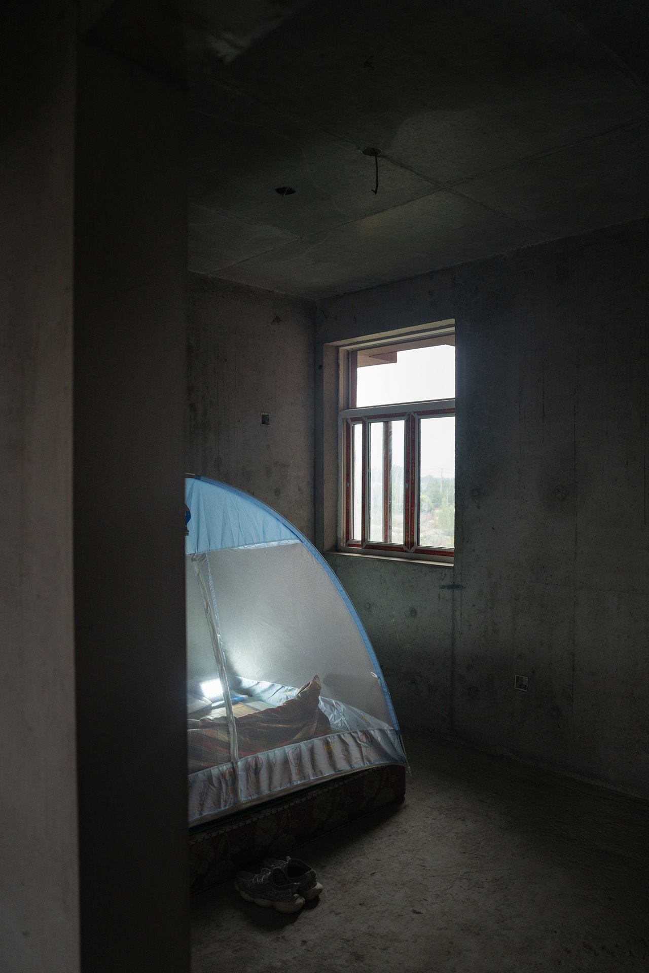 Summers in Xi&rsquo;an, China are hot and humid. This particular unfinished home did not have windows or doors installed. The homeowner installed his own windows and set up nets to keep mosquitos away.&nbsp;