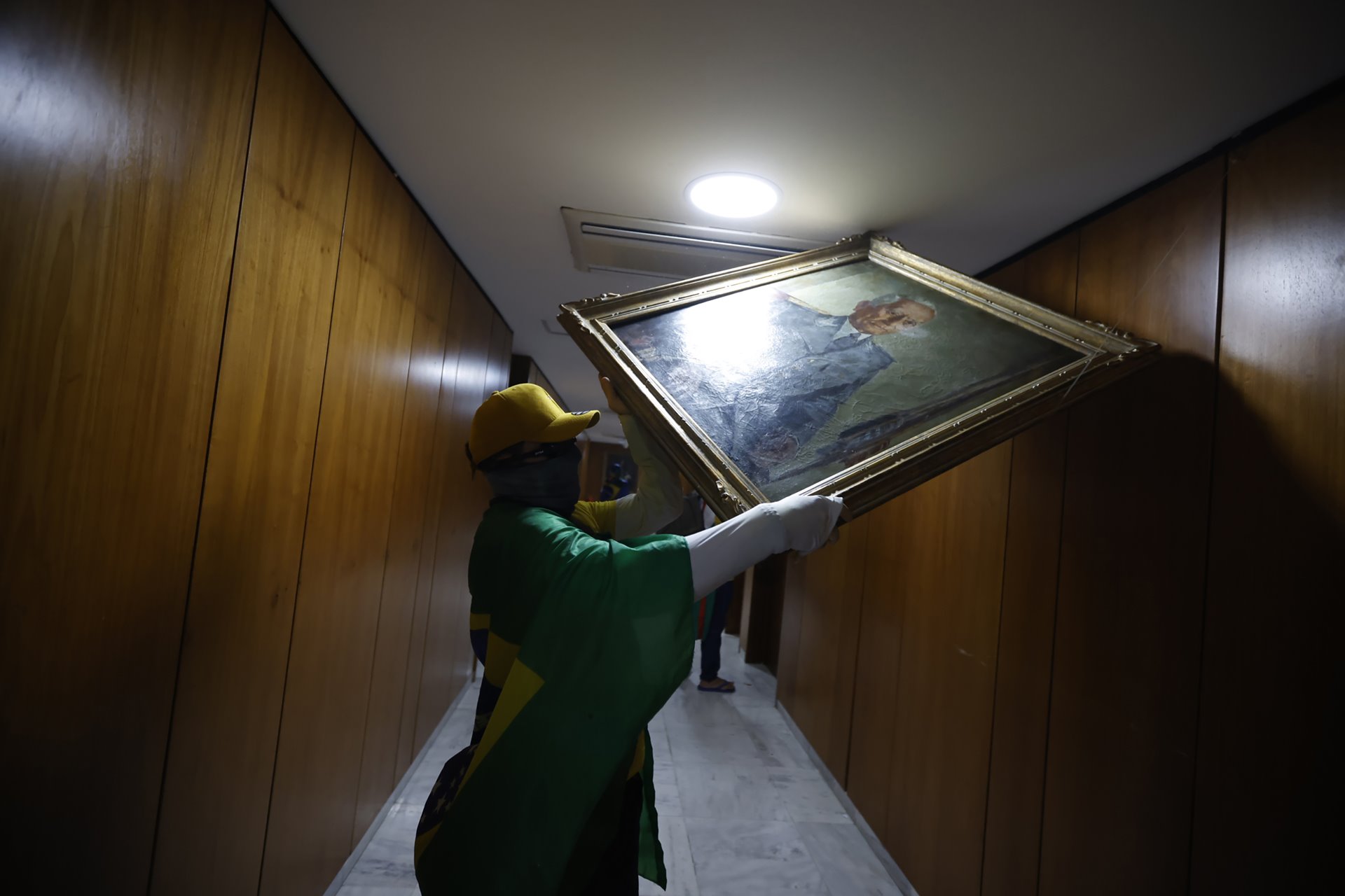 A protestor removes a painting from the wall inside a federal building, in Brasília, Brazil. Dozens of art pieces were vandalized or destroyed in the three federal buildings.&nbsp;