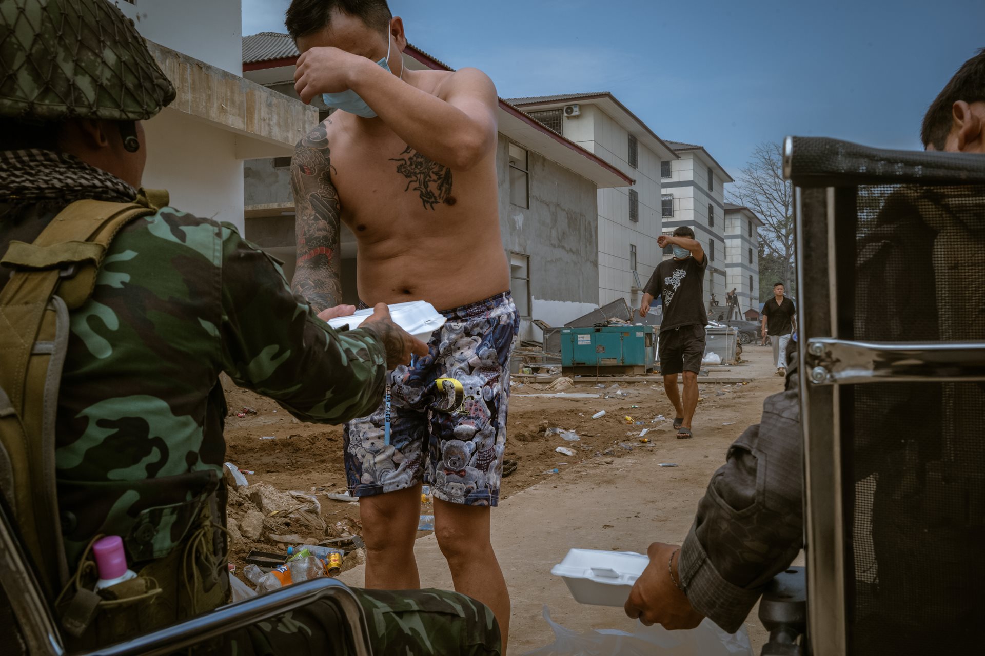 Workers cover their faces as they receive food rations from Karen National Liberation Army soldiers. The &ldquo;liberation&rdquo; of the camp turned many scam center employees into refugees who wanted to avoid being identified by international law enforcement or their former captors. Min Let Pan, Myanmar.