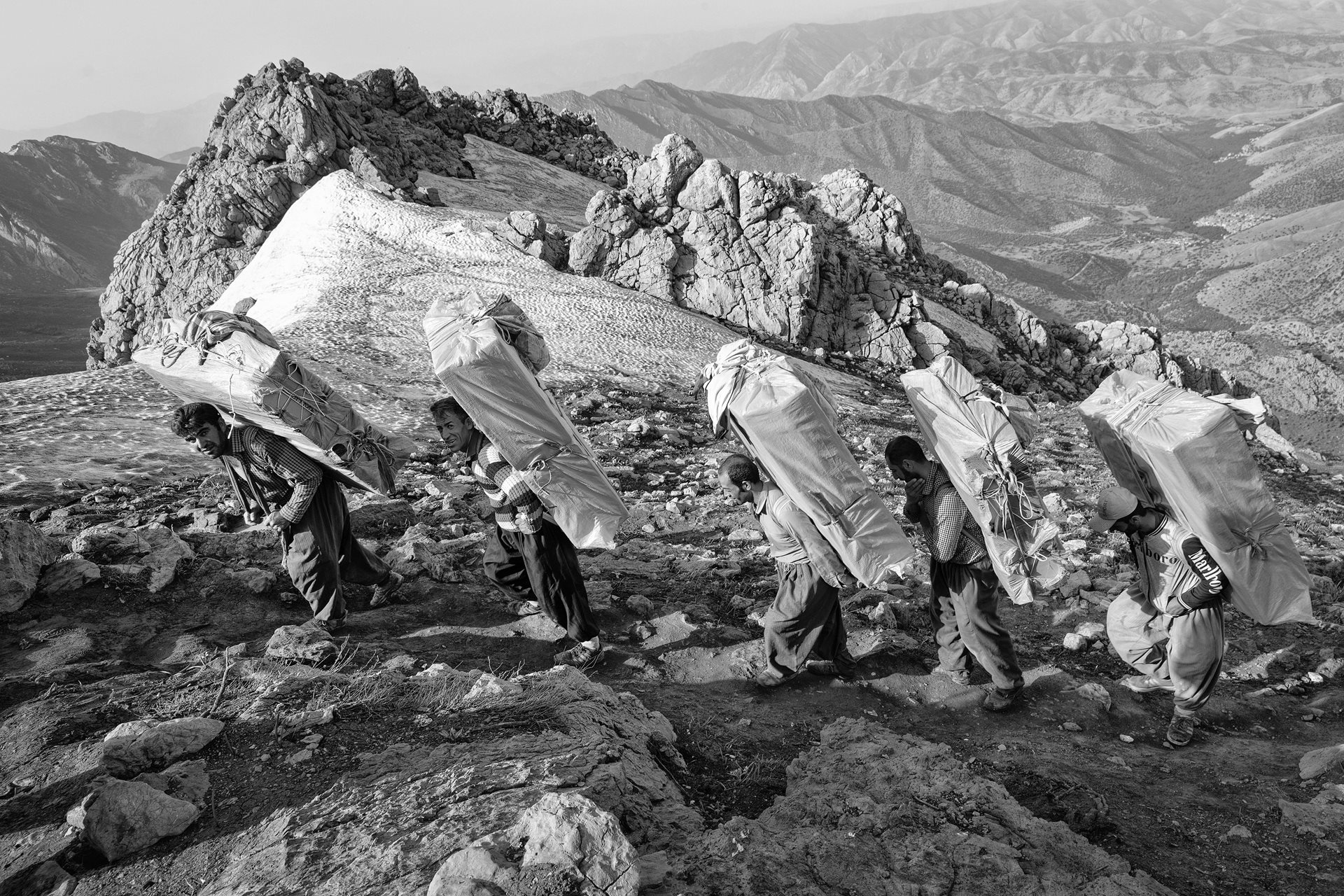 Kolbars in Kurdistan, Iran, often carry goods like cigarettes, home appliances, and European clothing for large business and shop owners who freely resell them in Iran, feeding a black market.