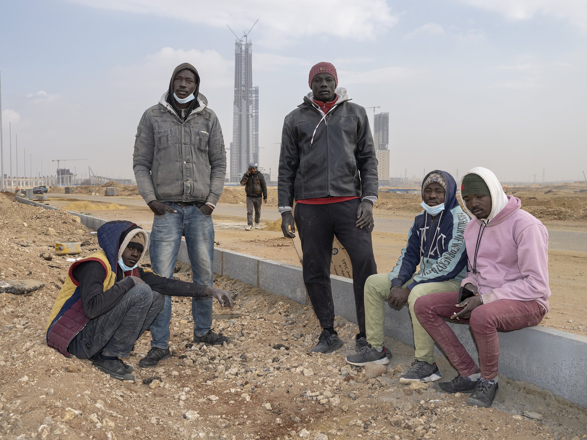 <p>Mahfouz Abib, John Madesto, Angelo Saimon, Abdel Baset Omar, and Mosab Abdel Wahab (left to right), workers from South Sudan, pose in front of the Iconic Tower rising in Egypt&rsquo;s New Administrative Capital, under construction near Cairo. An estimated two to five million people of Sudanese origin live in Egypt.</p>
