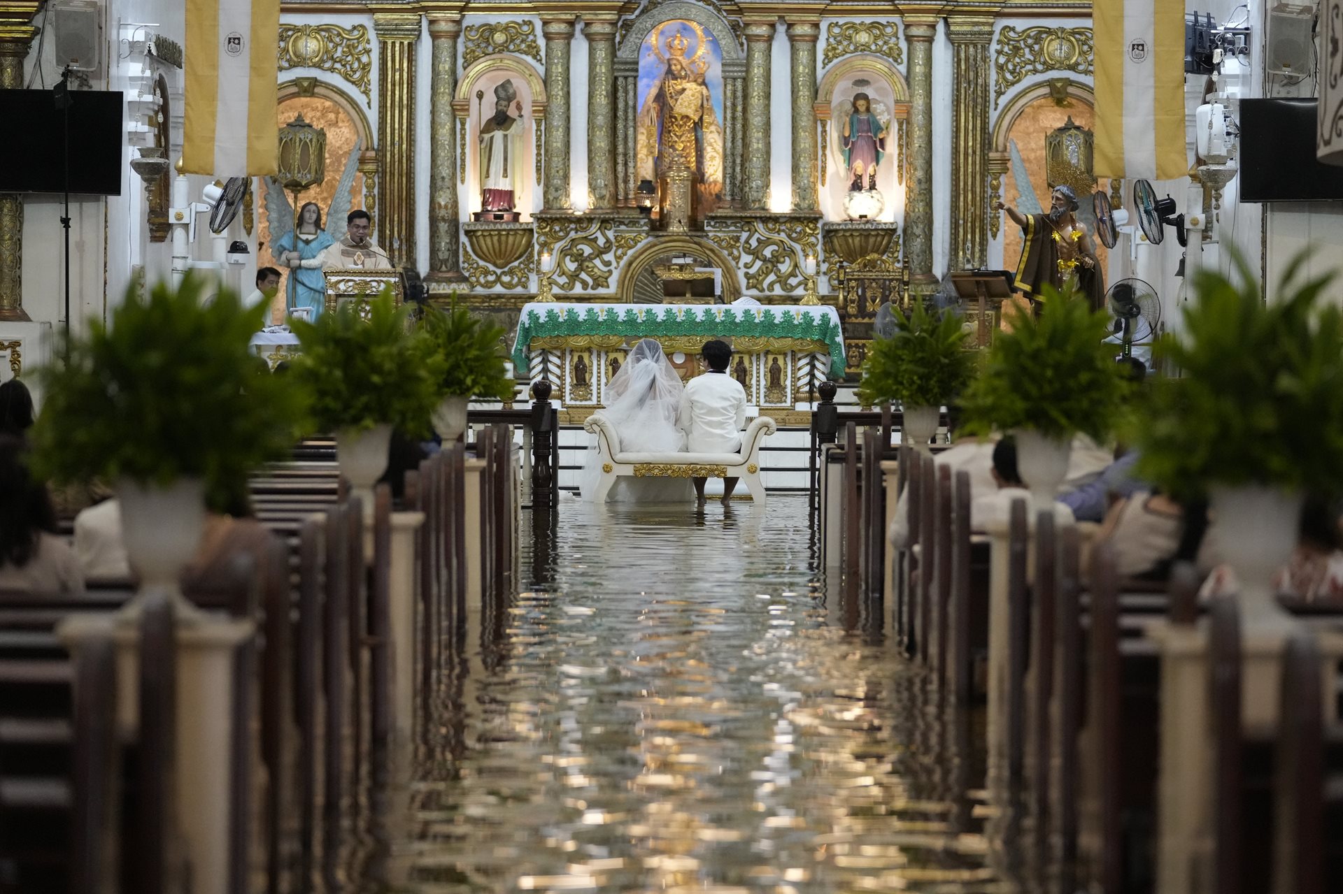 Jade Rick Verdillo and Jamaica Aguilar sit before the altar in Barasoain Church. After a ten-year courtship, the couple embraced the flood as one of the challenges to navigate in a relationship. Malolos, Bulacan province, Philippines