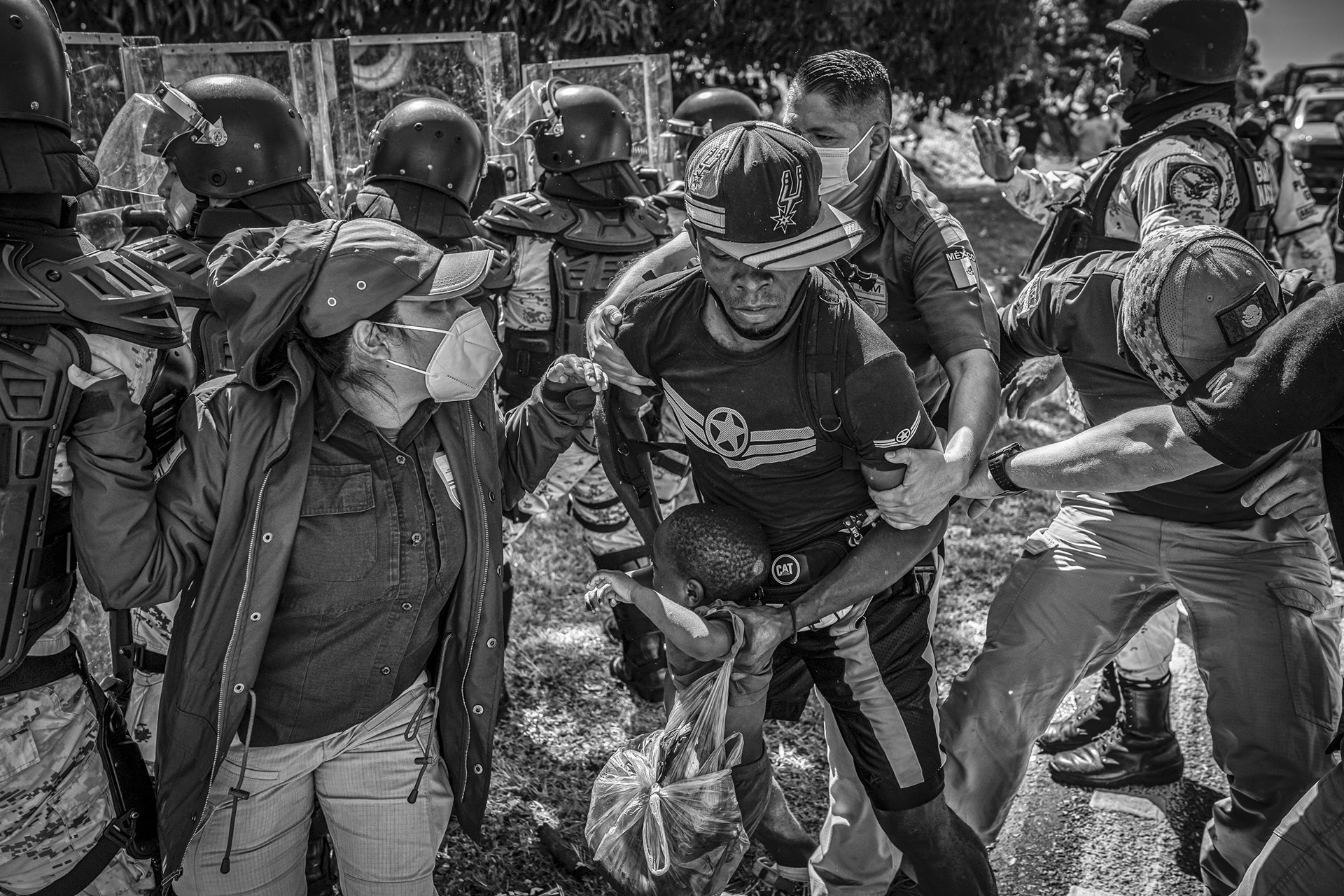 A Haitian migrant struggles against Mexican migration officers during a massive raid on a migrant caravan composed primarily of Haitians, Mapastepec, Mexico. Detainees are brought to Siglo XXI migratory station where, according to several NGOs, they face human rights violations. The station operates like a detention center, where individuals, deprived of rights, are swiftly deported to Guatemala, regardless of nationality.&nbsp;