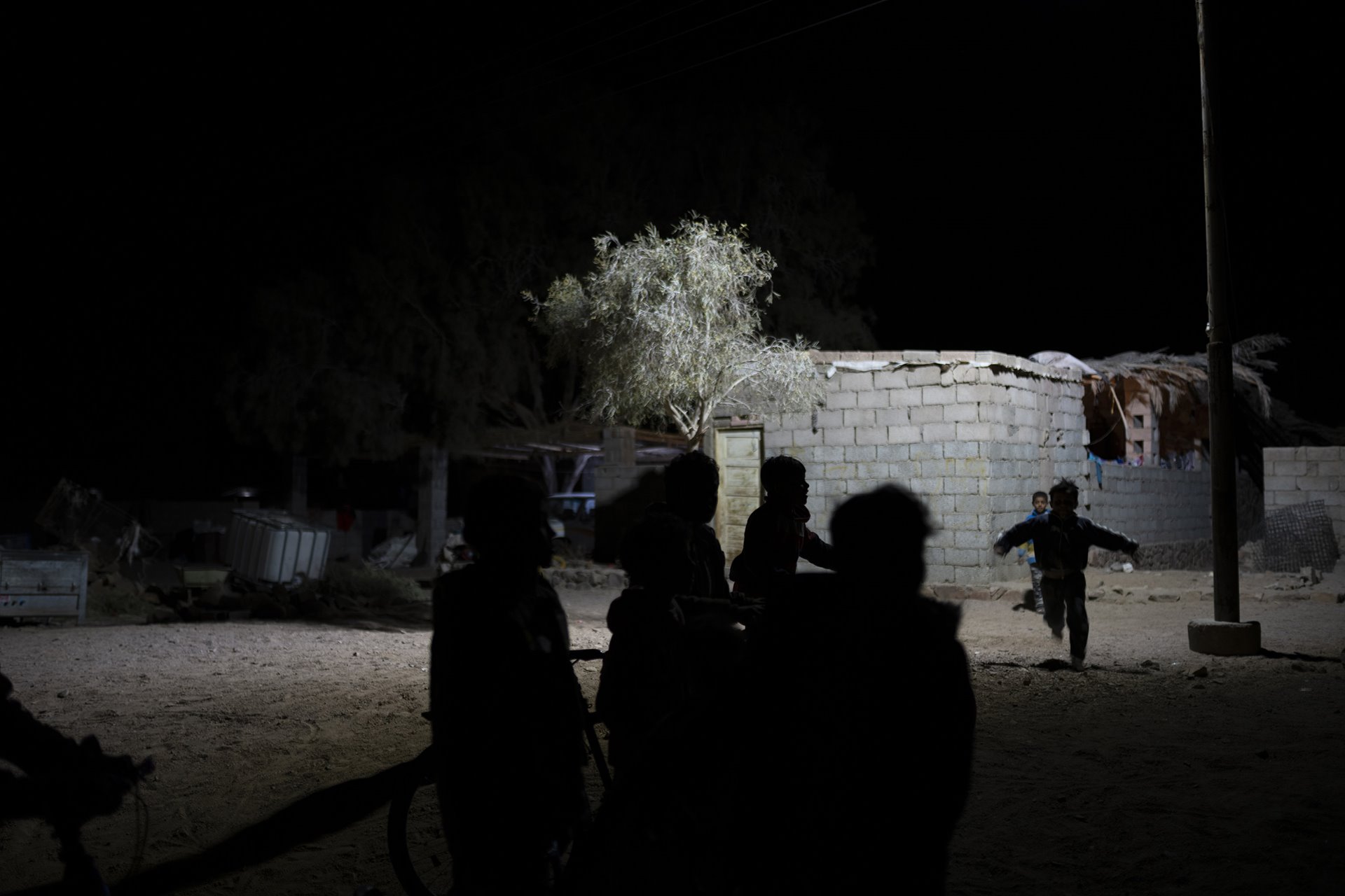 Children play at night in St. Catherine, South Sinai, Egypt. Due to a lack of enough electricity and resources, the day ends at nightfall. Children often remain awake and play underneath the few streetlights in their village.