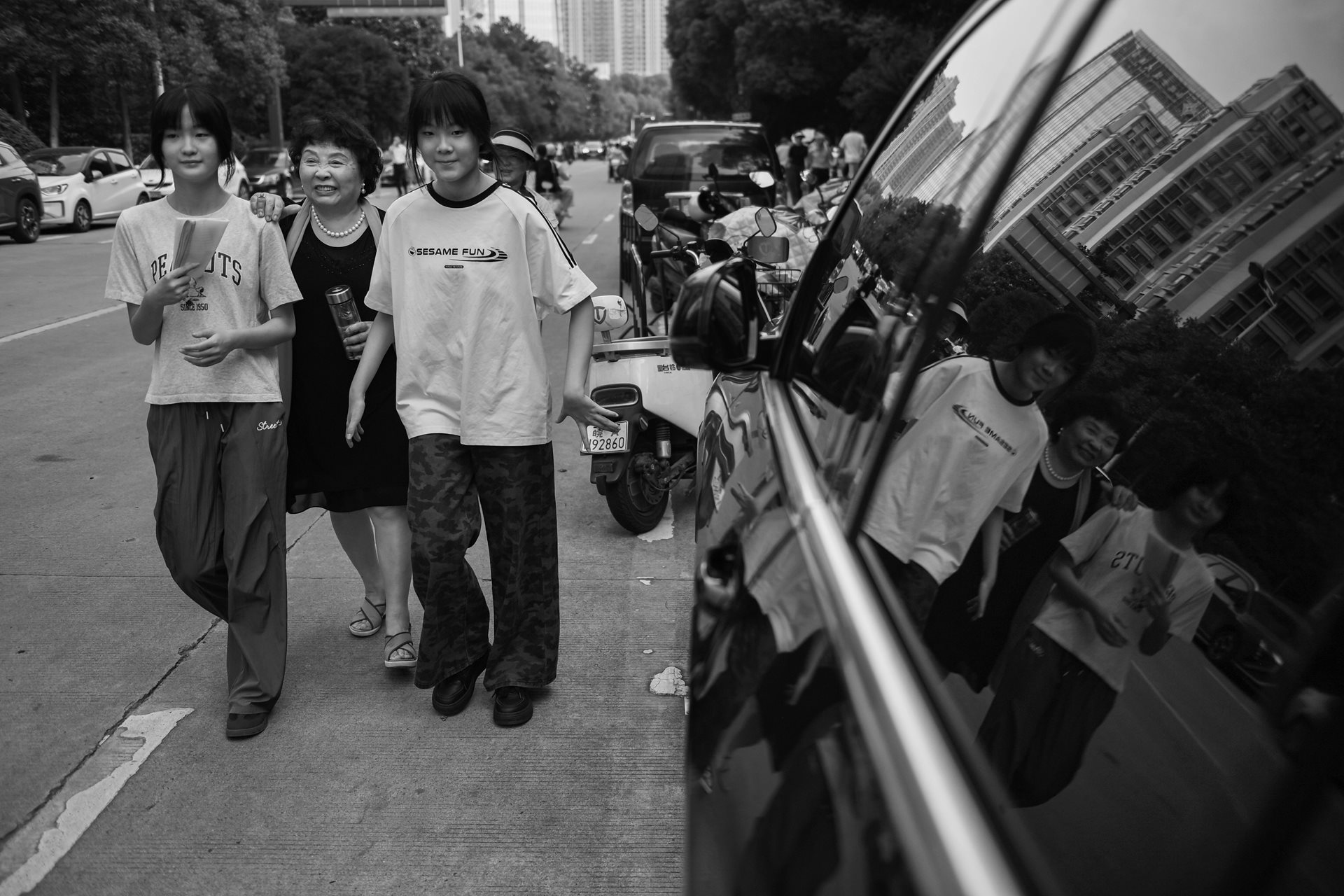 Sheng Hailin accompanies the twins to the examination venue to familiarize them with the location. Her presence at these events remains a unique sight among the younger parents in the crowd. Hefei, Anhui Province, China.