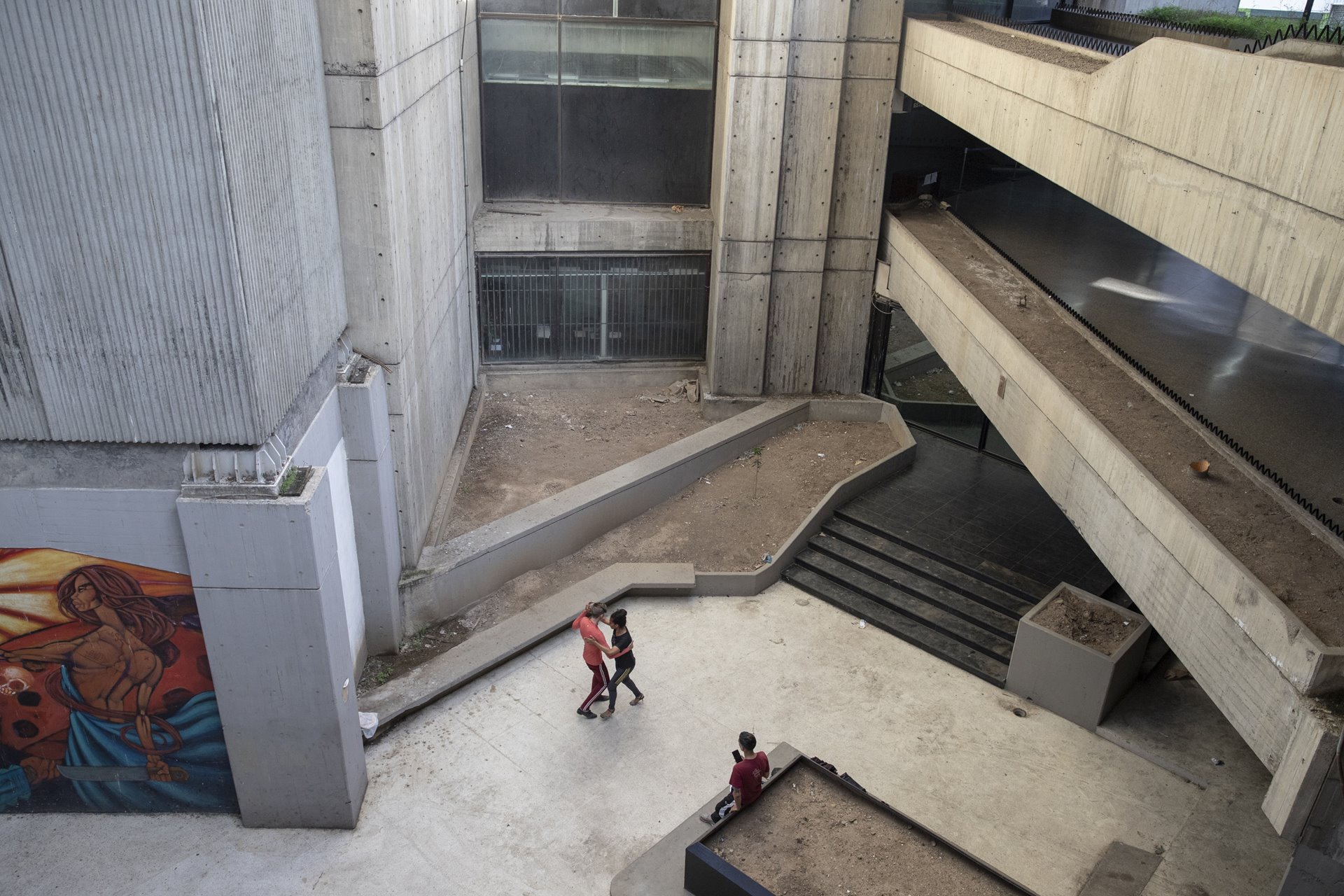 <p>A couple dances the tango in a Parque Central courtyard in Caracas, Venezuela. Built in the 1970s, the complex was once a prestigious address, with two towers that until 2003 held the title of tallest skyscrapers in Latin America. Now the buildings leak, are badly maintained, and insecure.</p>
