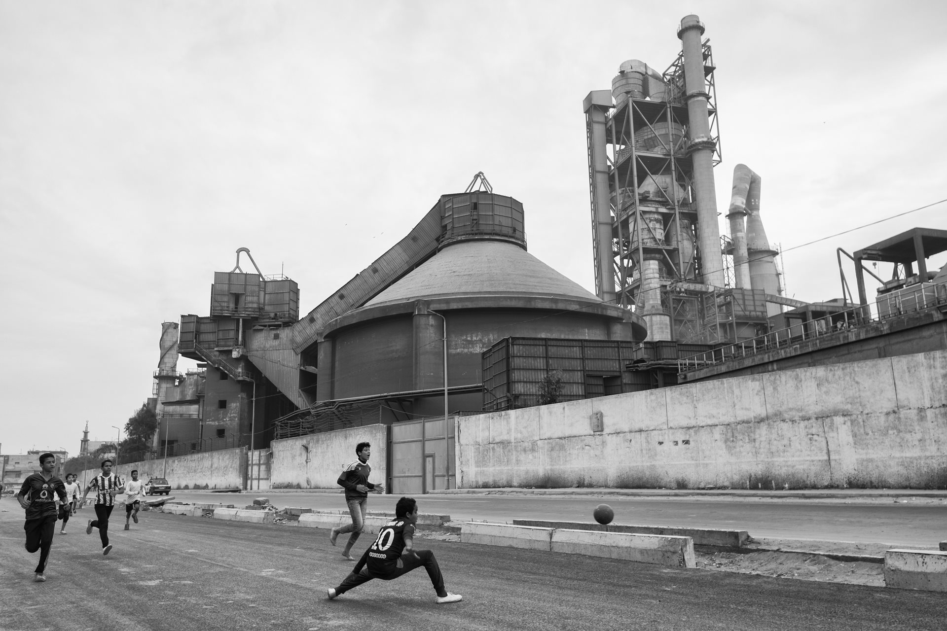 Children playing soccer in front of the Titan cement factory in Moon Valley, Alexandria, Egypt.