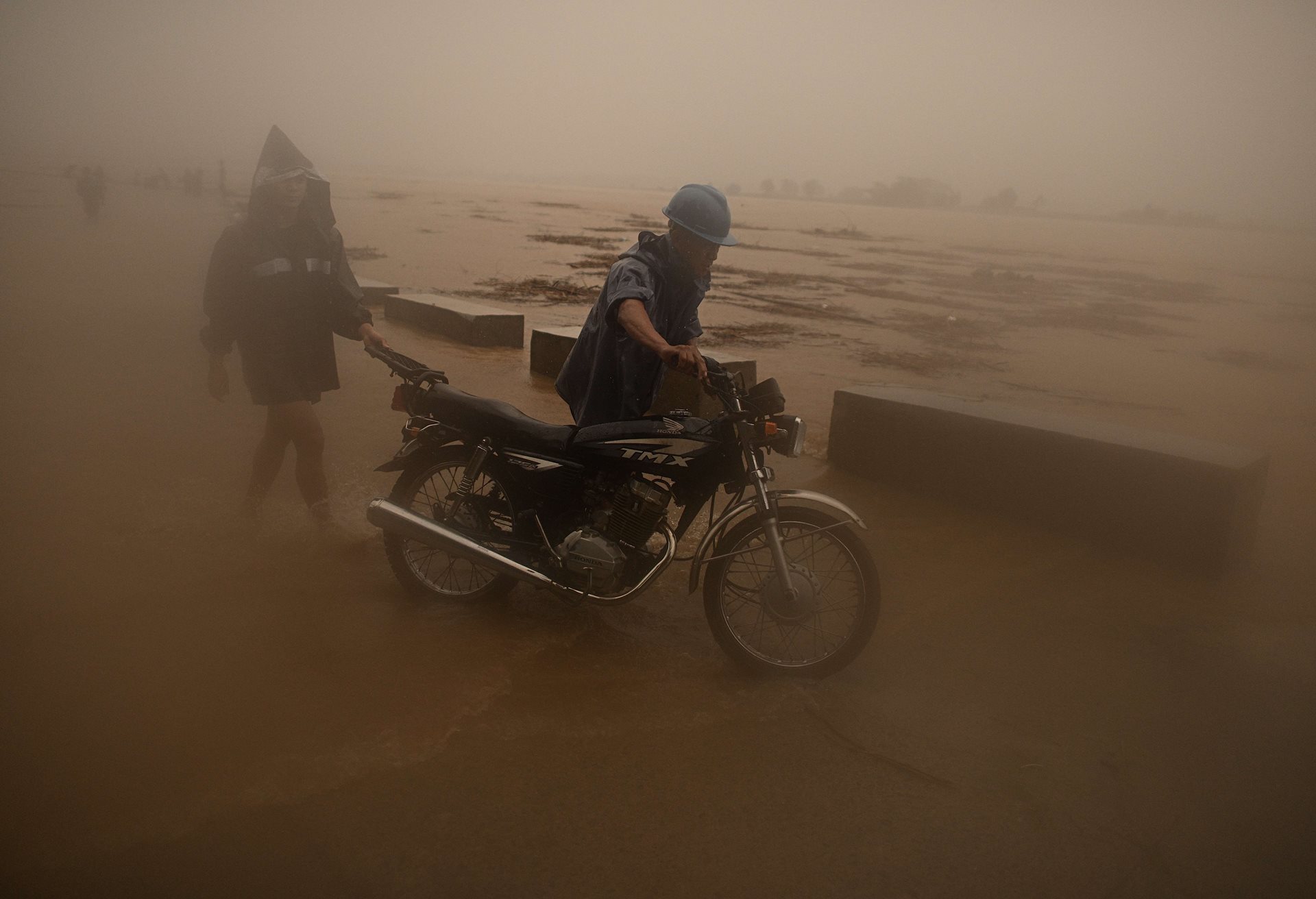 A man pushes his motorcycle beside a river swollen by heavy rains from Typhoon Toraji, in Ilagan City, Isabela, northern Philippines. The typhoon led to the evacuation of residents and the closure of ports in the region.<br />
&nbsp;