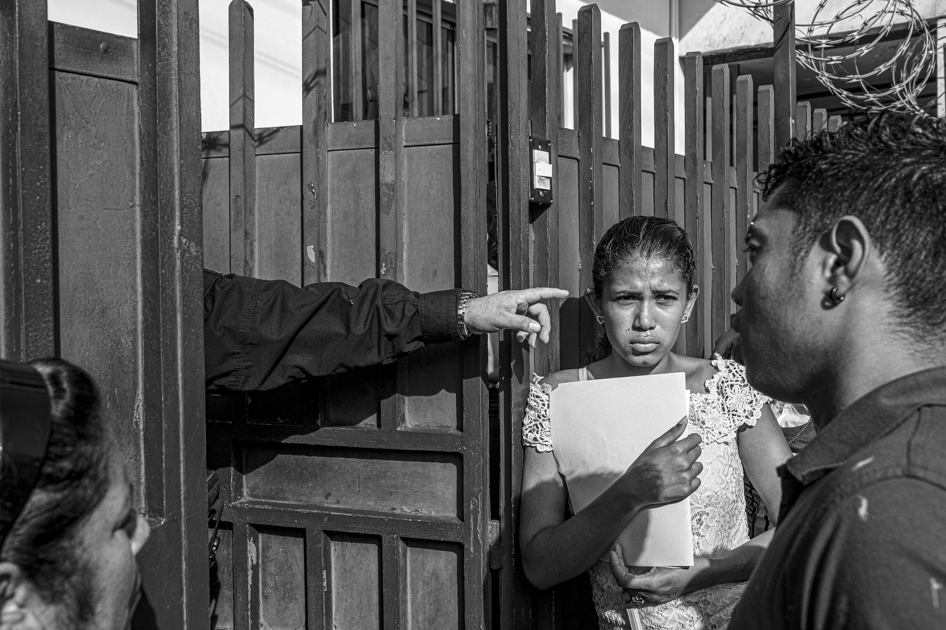 Asylum seekers wait at the gates of the Mexican Commission for Aid to Refugees (COMAR) for a hearing that will grant them a humanitarian visa to stay in Mexico or travel across the country to the United States. COMAR has been accused of corruption and stalling the approval of humanitarian visas. Tapachula, Mexico.