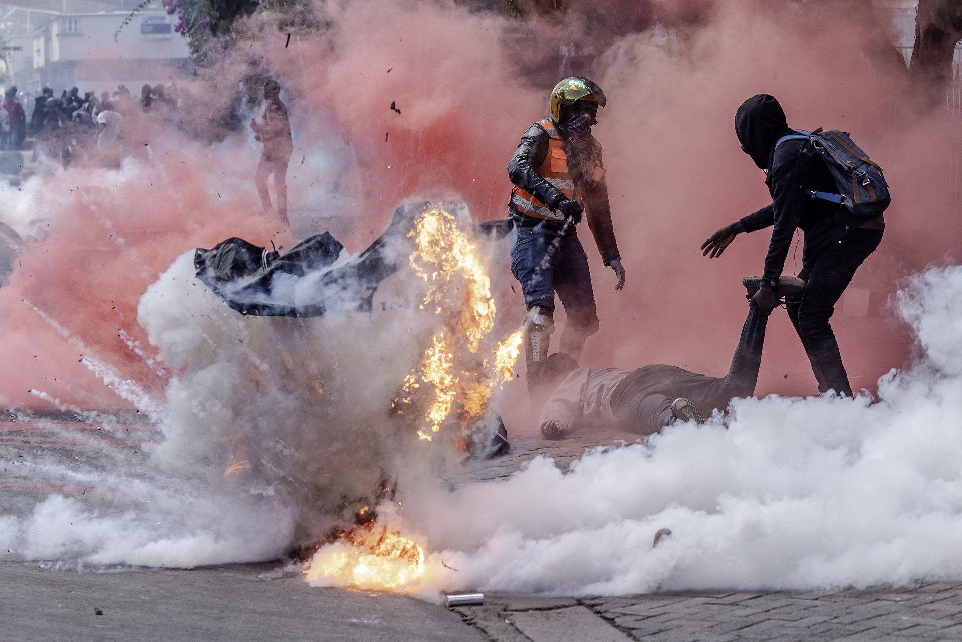 Two protestors helping injured people are hit with tear gas outside the Kenyan Parliament during a national strike against the Finance Bill 2024 in Nairobi, Kenya.