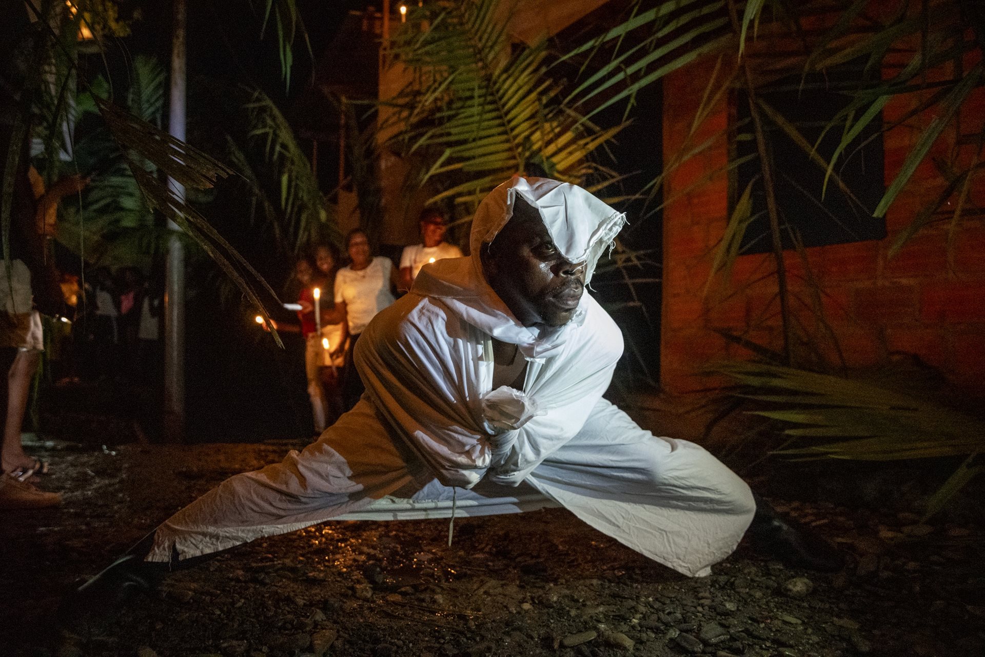 Luis Aramburo dresses in a white sheet to represent the <em>Ánimas Solas</em> (solitary souls) in Juntas, Buenaventura, Colombia. Trembling and whispering, he descends to prepare the community for the arrival of the Manacillos.&nbsp;