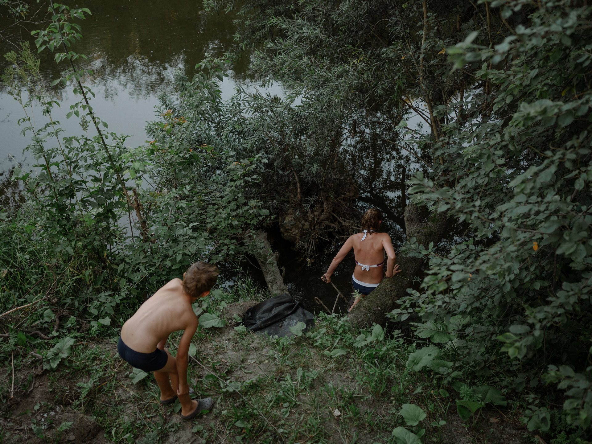 Aliona&rsquo;s sister Sanya swims with her son in the Ushayka River, which runs past the family dacha (country cottage), in Tomsk, Russia. Once gold was washed in the Ushayka, but nowadays the water barely reaches their waists, and they are happy if they manage to find the polluted river free of old tires and rusty metal.&nbsp;