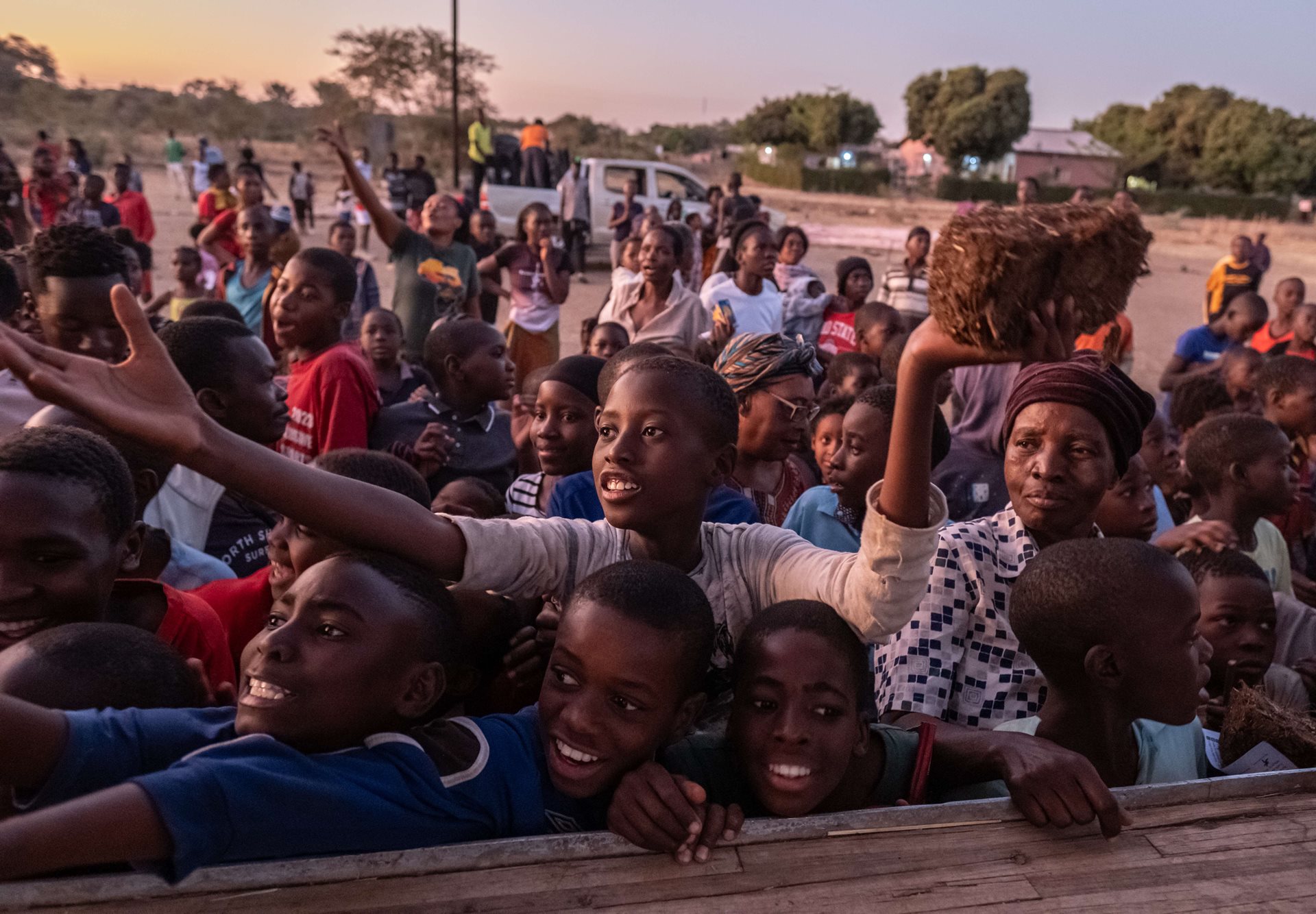 Youths clamor for &ldquo;chili bricks&rdquo; to deter elephants at a public safety event in Livingstone, Zambia. The bricks, made of elephant dung, used engine oil, and chili, produce a noxious smoke when burned that helps deter elephants.