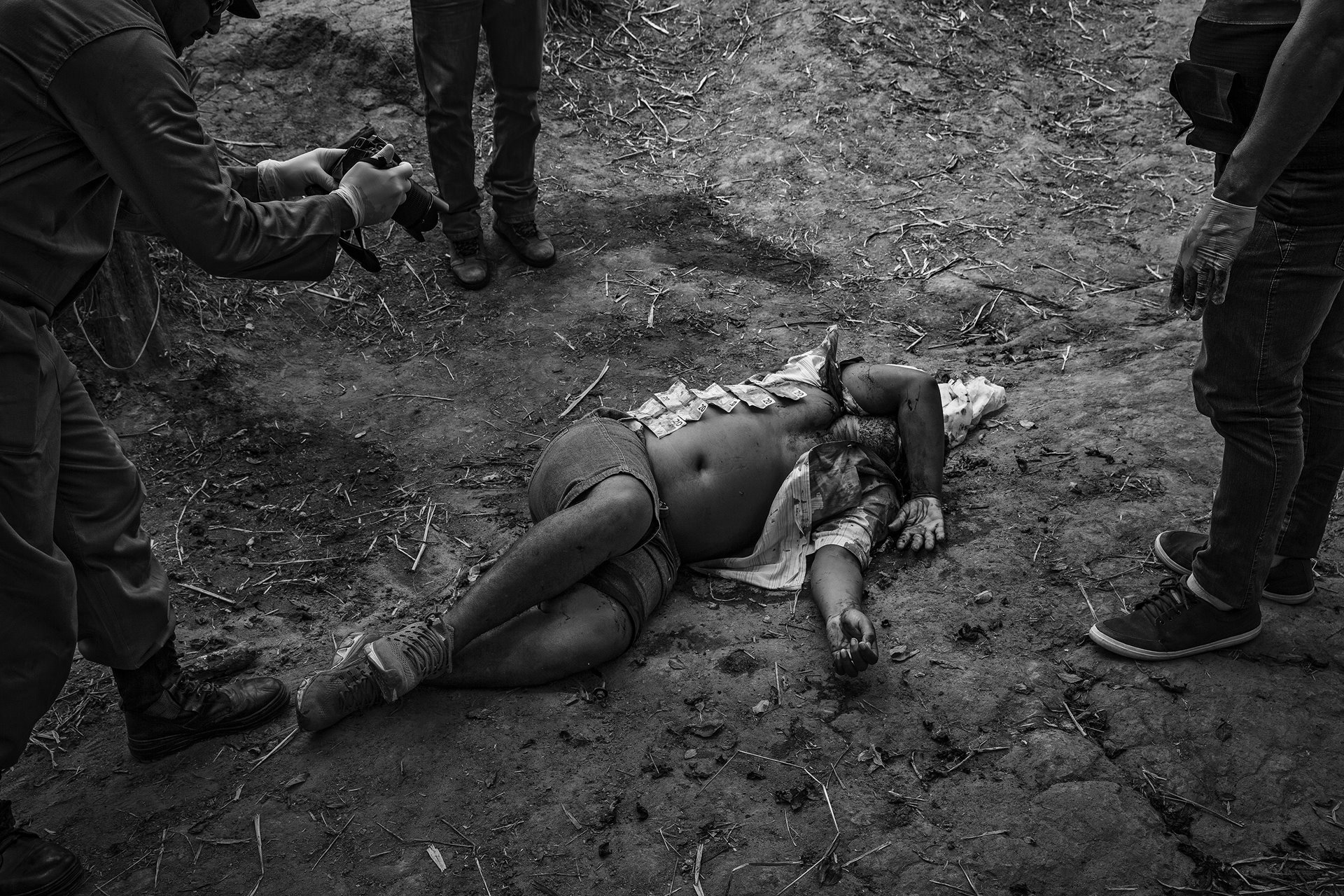 Police officers examine the body of a man killed in rural Altamira, near the Belo Monte Dam, Pará, Brazil. They have laid out banknotes found on the dead man, which they say indicates this was not a robbery but an extra-judicial killing. The 2017 Violence Atlas, published annually by Brazil&rsquo;s Institute of Applied Economic Research (IPEA), ranked Altamira as Brazil&rsquo;s most violent city.