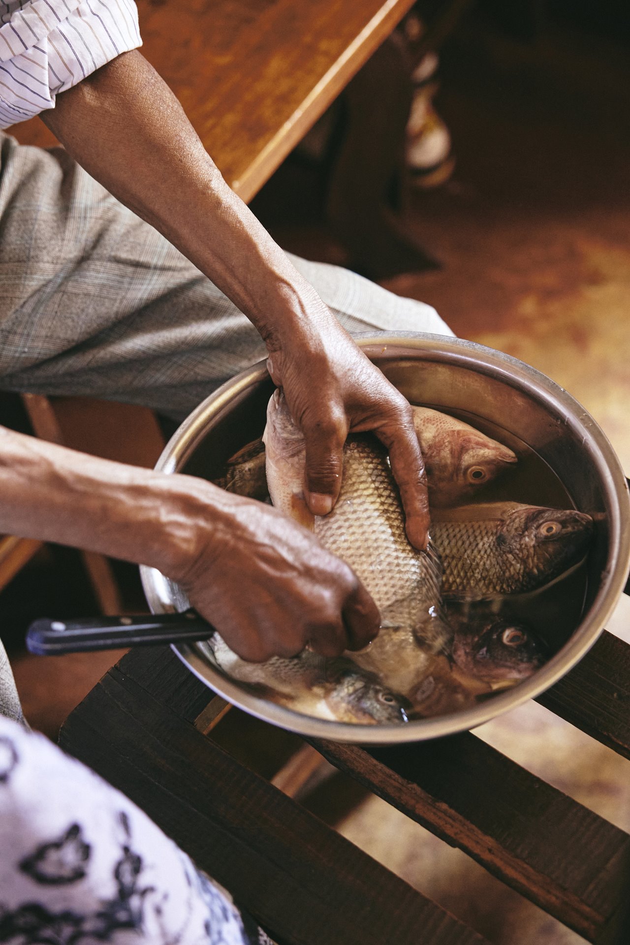 Dada Paul cleans fish for the family meal after attending church on Sunday, in Antananarivo, Madagascar. He has always loved this task, though these days sometimes puts the fish aside afterwards and forgets he has already cleaned it.