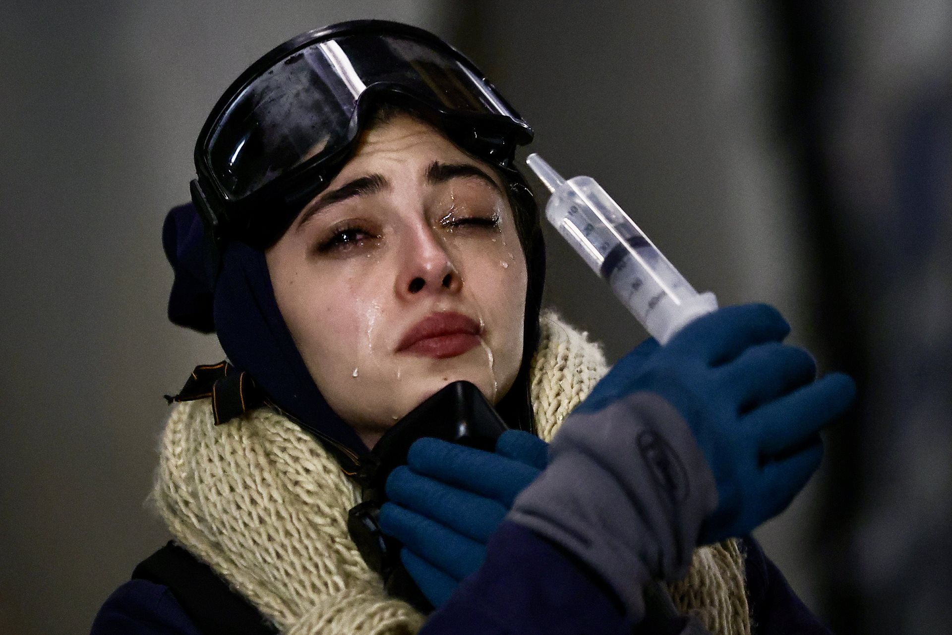 A protester rinses her eyes after police have deployed tear gas, in Tbilisi, Georgia. She wears a protective ski mask, respirator, and gardening gloves (to pick up hot gas containers).