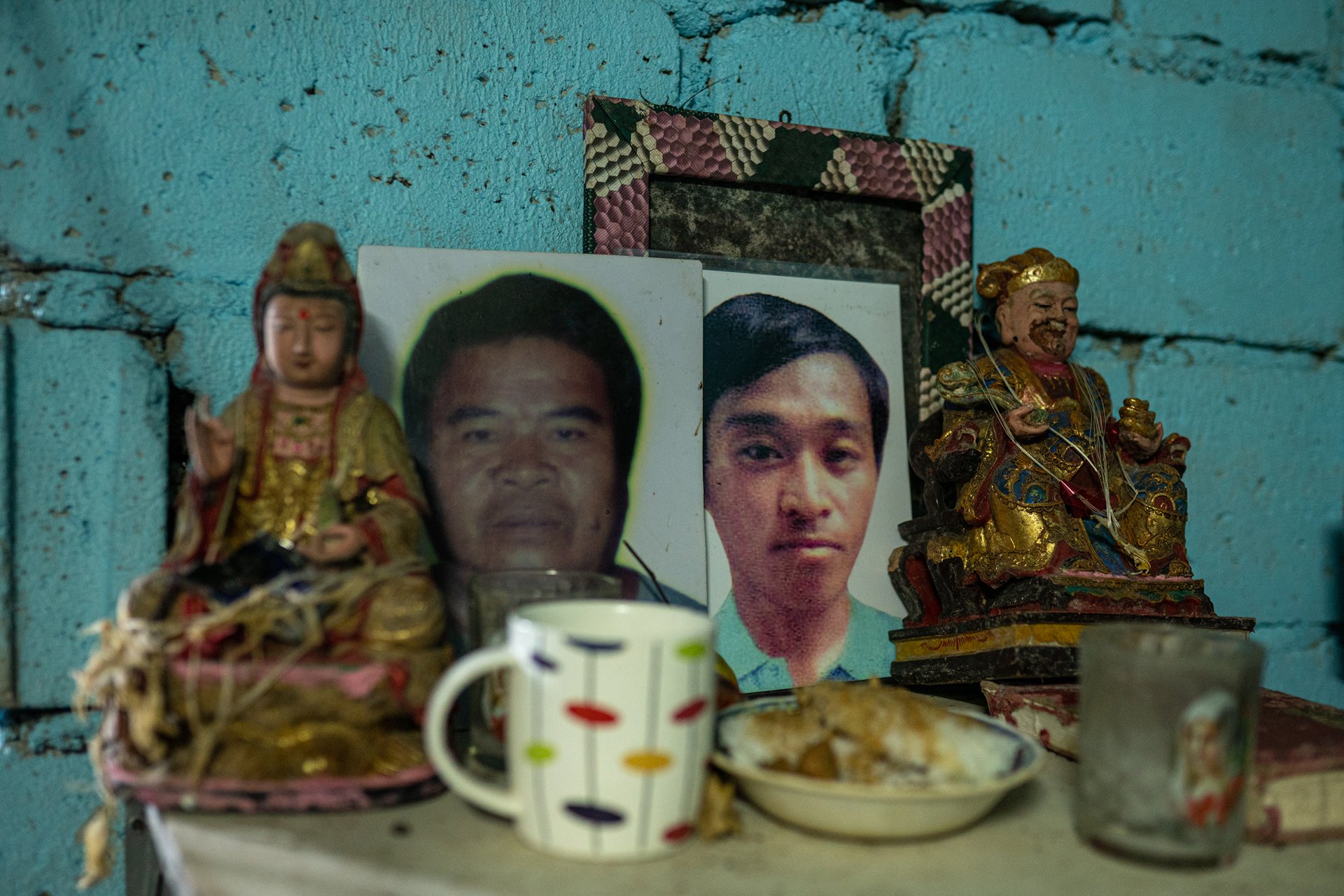 Food offerings lie before photographs of Anita Lerio&rsquo;s husband and son, at a household altar in Tondo, Manila, the Philippines. Her son Julius was killed in 2017, while her husband, Bugo, was killed in 2019. Since then, Anita had undergone counseling for families of war-on-drugs victims.