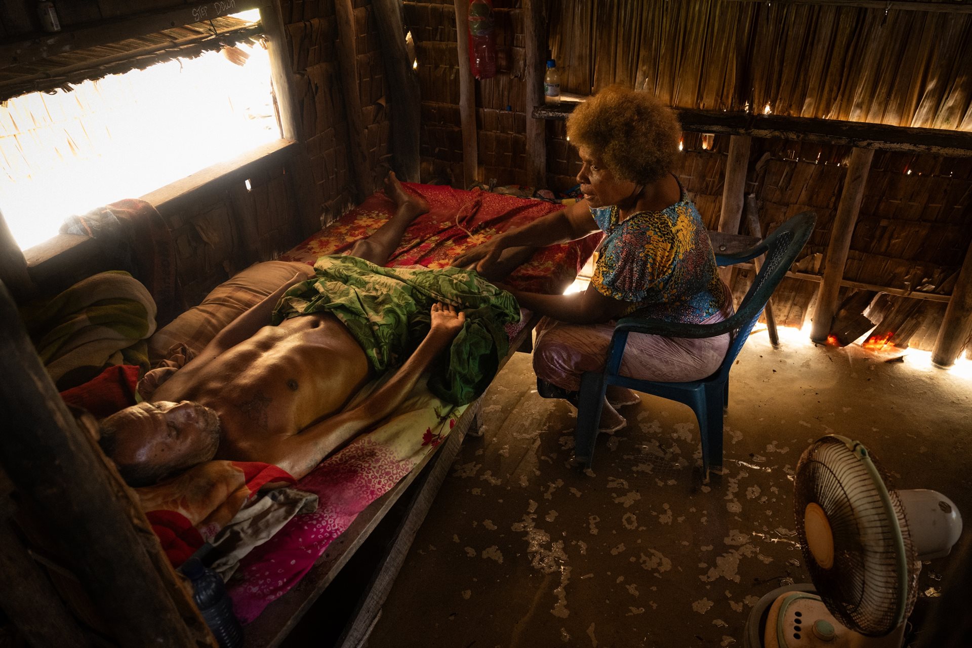 Eddie Sua, a paralyzed former hunter, lies in his hut which frequently floods during high tides. In remote Fanalei, basic medical care requires a 30-minute canoe trip across the lagoon. Fanalei Village, Fanalei Island, South Malaita, Solomon Islands.