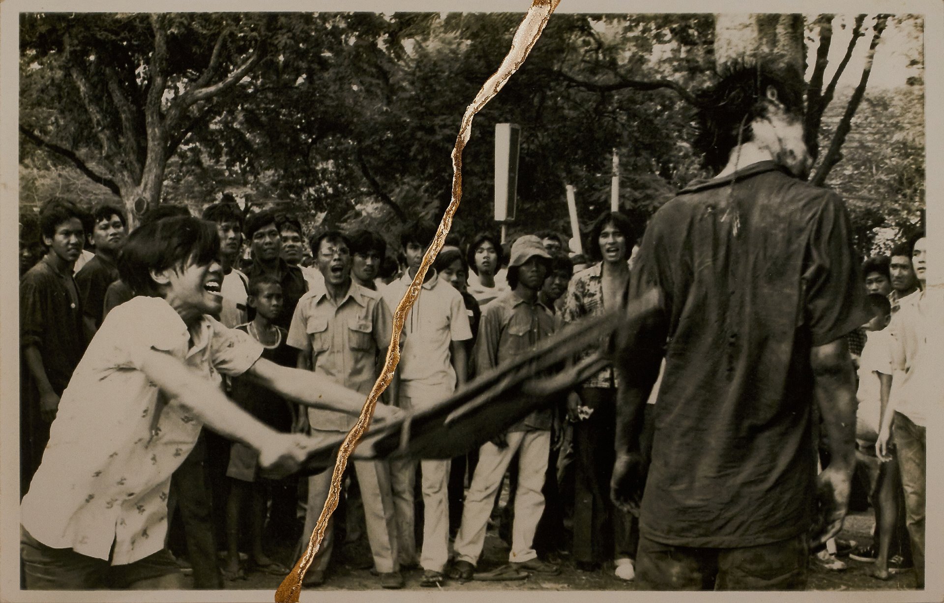 A battered corpse hangs from a tree as a man swings a folding chair into the body in Bangkok, Thailand.&nbsp;<br />
<br />
On 22 October 2018, the Thai group <em>Rap Against Dictatorship </em>released the song <em>My Country Has&hellip;</em>. The video has a scene where a man beats the corpse of a student that has been hanged from a tree. With over 100 million views, this re-enactment introduced the massacre to many more people of the younger generation.&nbsp;