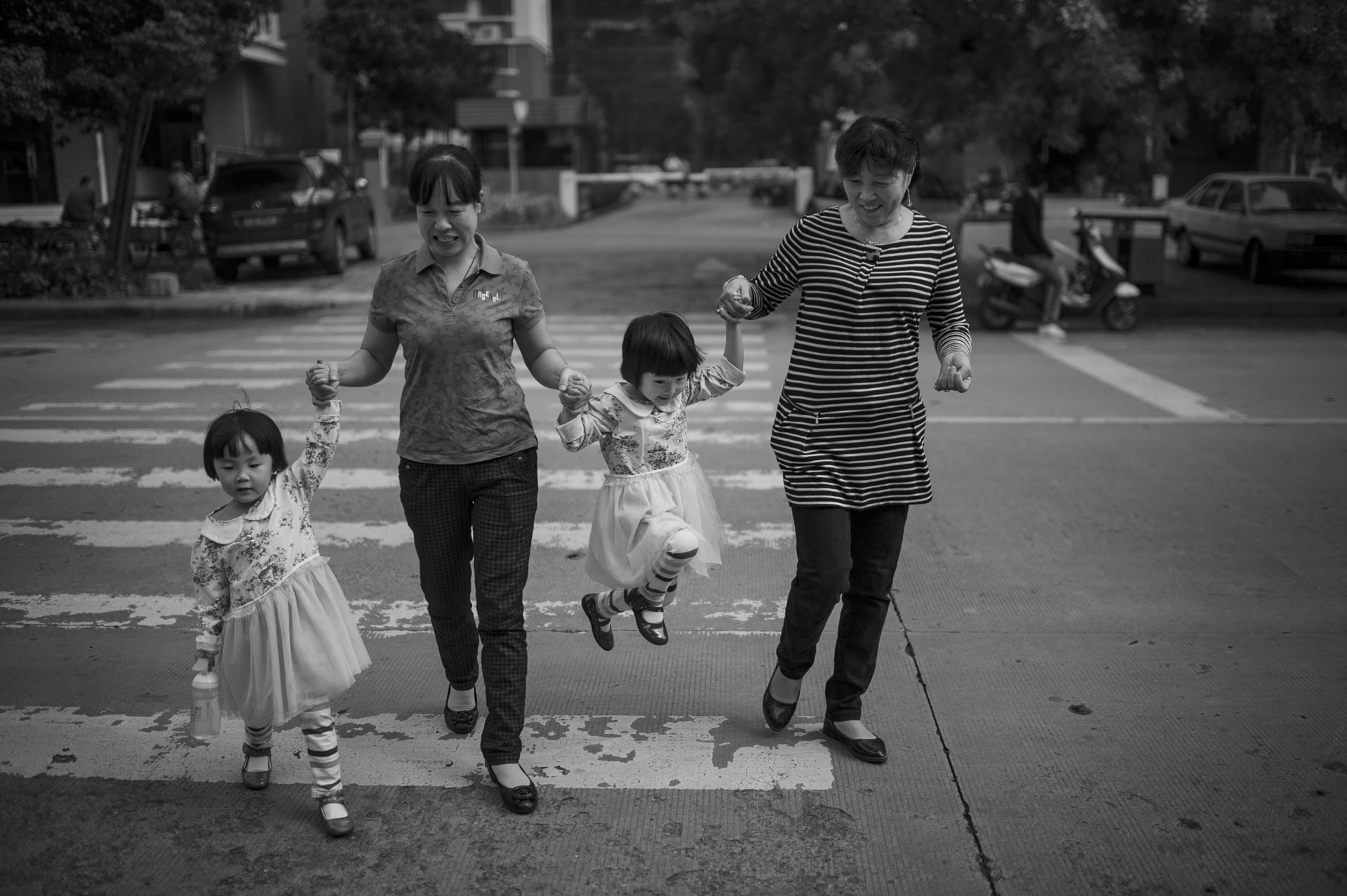 Auntie Zeng (left) and Auntie Li (right), two caretakers hired to assist in childcare, walk the twins to kindergarten in Hefei, Anhui Province, China. The high cost of childcare was a constant financial pressure on the family.&nbsp;