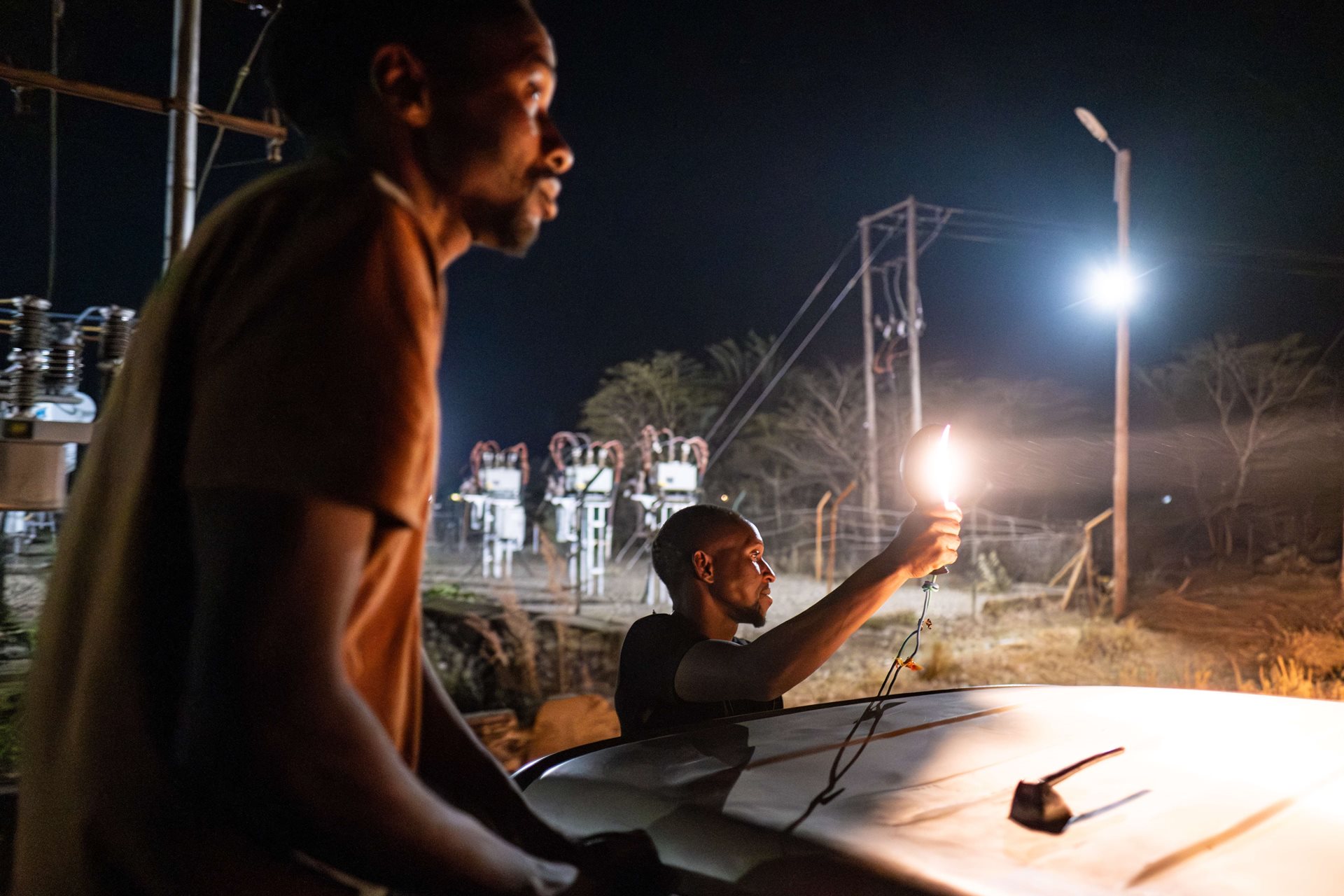 Mathews Chilambe (left) and Gift Ngandu (right), volunteers of the Elephant Response Team, search for elephants with their spotlights while on patrol, in Livingstone, Zambia.. During the dry season, when food within the national park is scarce for elephants, emergency calls from the community keep the team busy through the night.