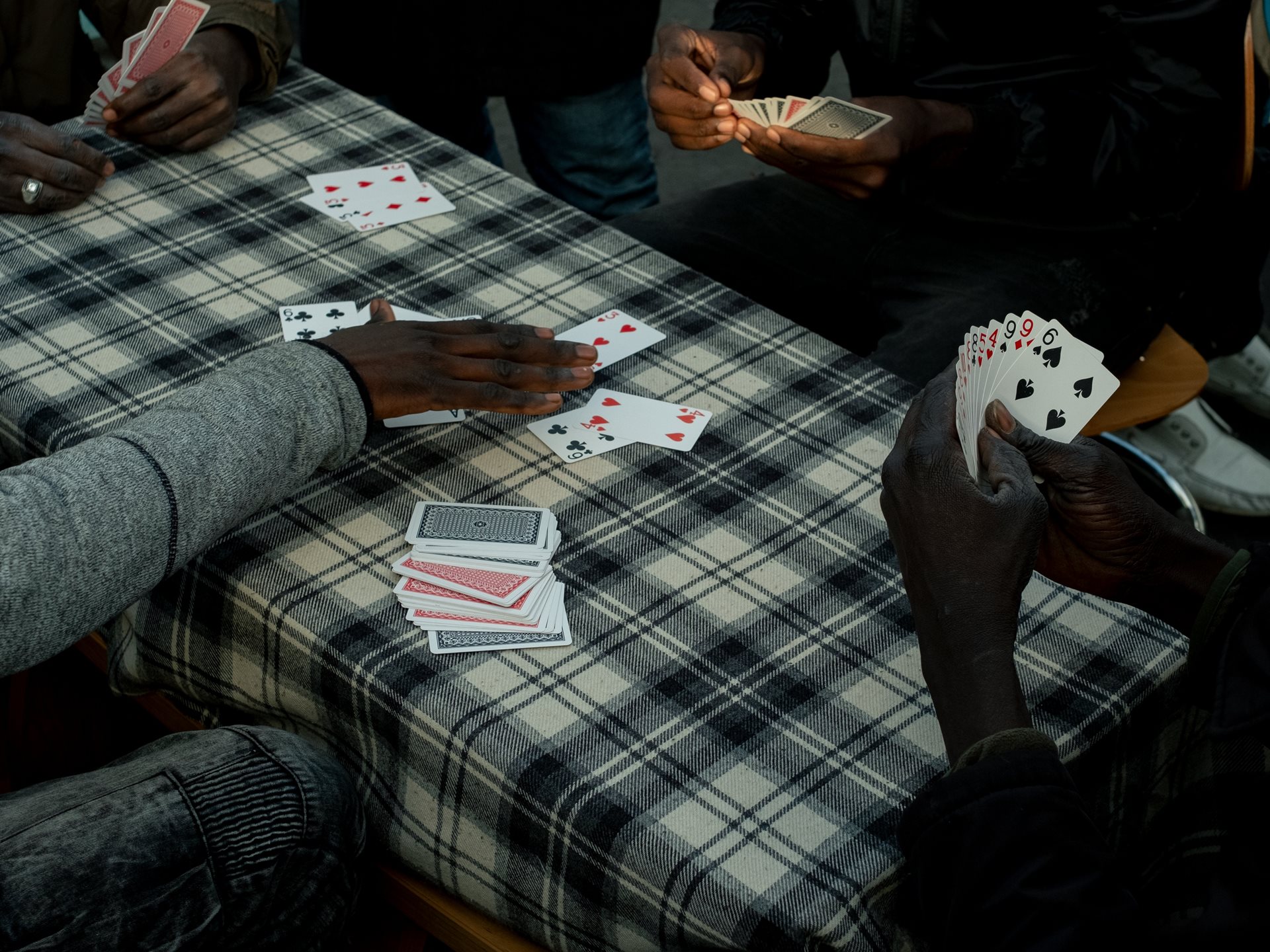<p>​​Sudanese migrants spend the afternoon playing cards at the Ecluse camp, an unofficial settlement opposite the Stade de France in Saint-Denis, France.&nbsp;</p>
