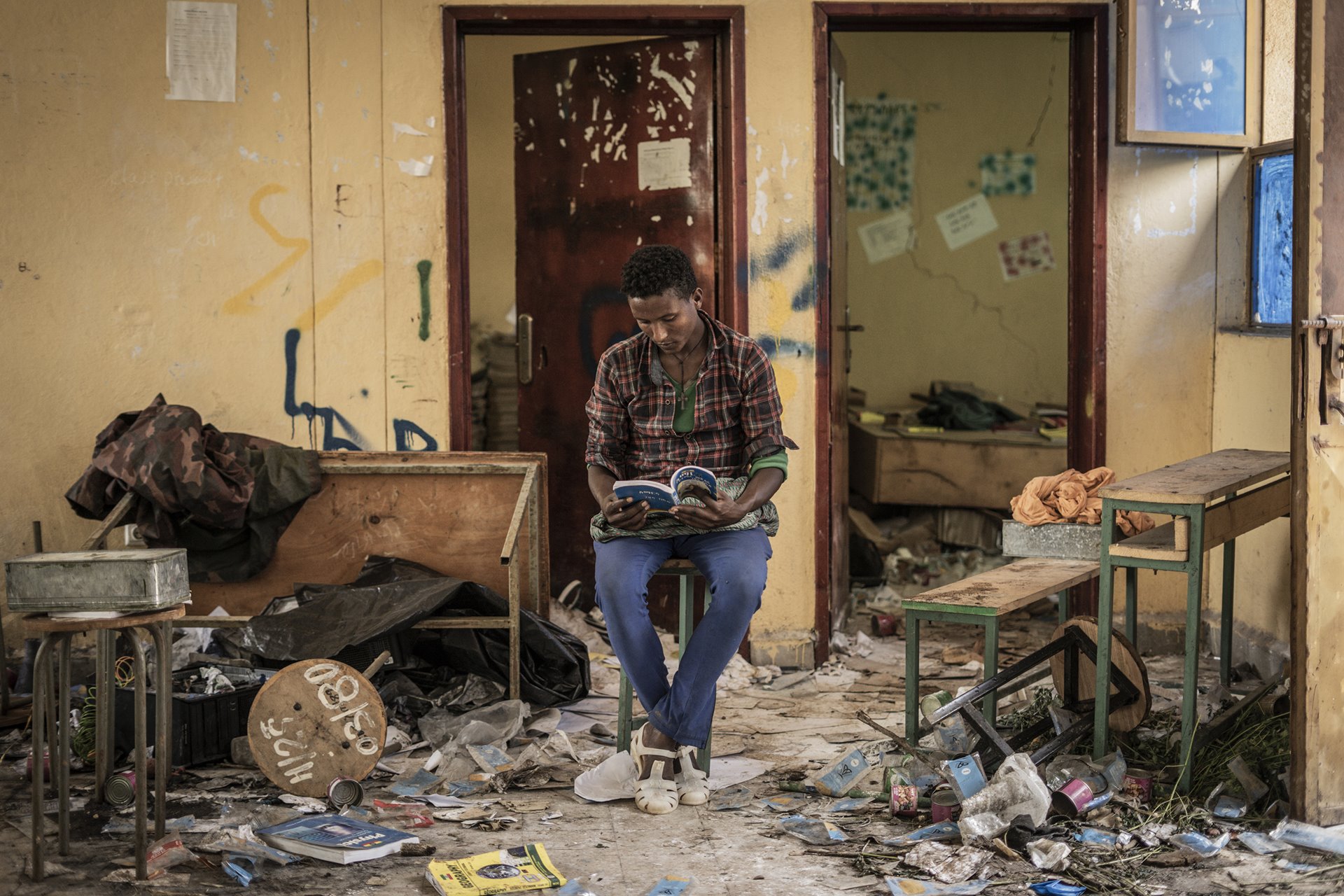 Kindu Fenta reads a book inside a classroom allegedly looted by pro-Tigray fighters, in Zarima, 140 kilometers from Gondar, Amhara, Ethiopia. Zarima is reported to have been the stage for a battle between Ethiopian and pro-Tigray forces.