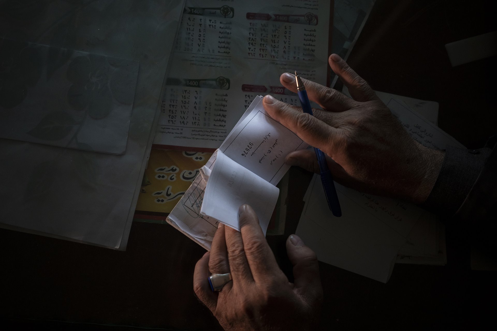 Abdul Malik Wahidi, who sells tickets at Ariana Cinema, in Kabul, Afghanistan, shows unsold tickets while browsing through them. The Taliban had ordered cinemas to stop operating nearly three months earlier.