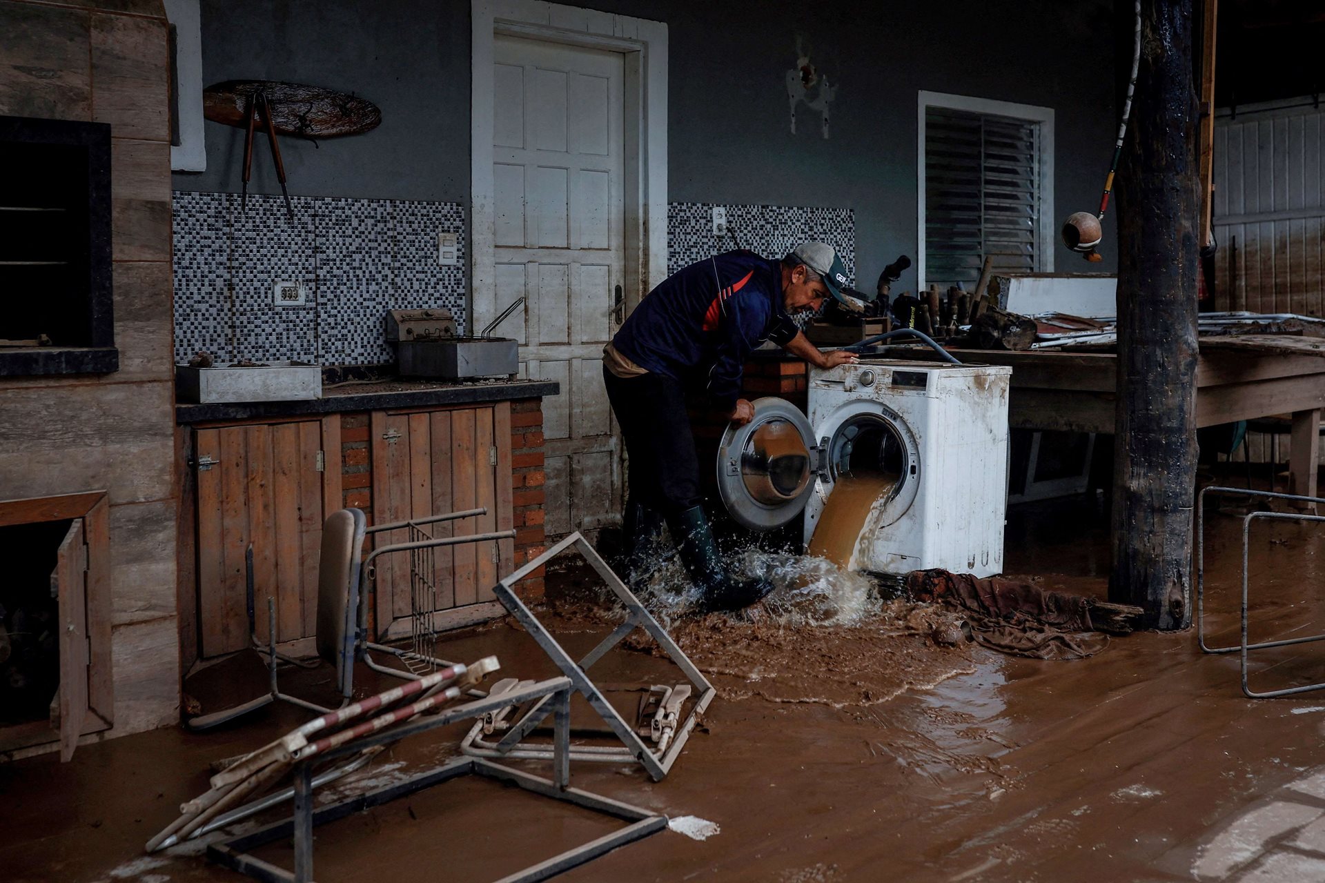 João Engelmann opens a washing machine full of muddy water after floods at the Integracao Gaucha settlement at his daughter&rsquo;s house. After three days of rain, Engelmann and his wife fled their home. Eldorado do Sul, Rio Grande do Sul, Brazil.