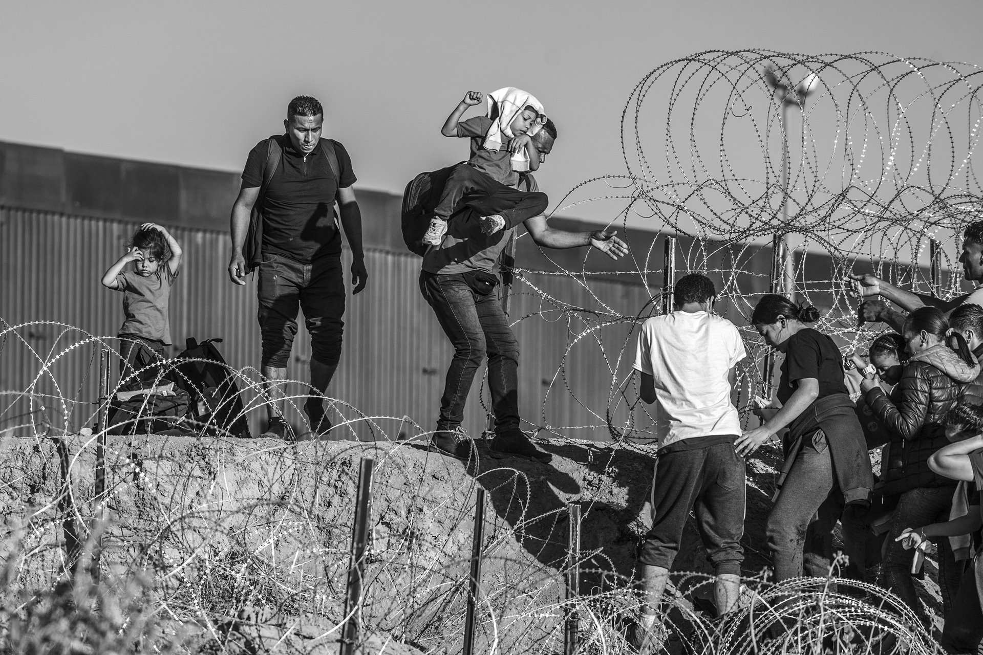 Migrants and asylum seekers attempt to cross a section of barbed wire set up by the Texas National Guard in Ciudad Juárez, Mexico.
