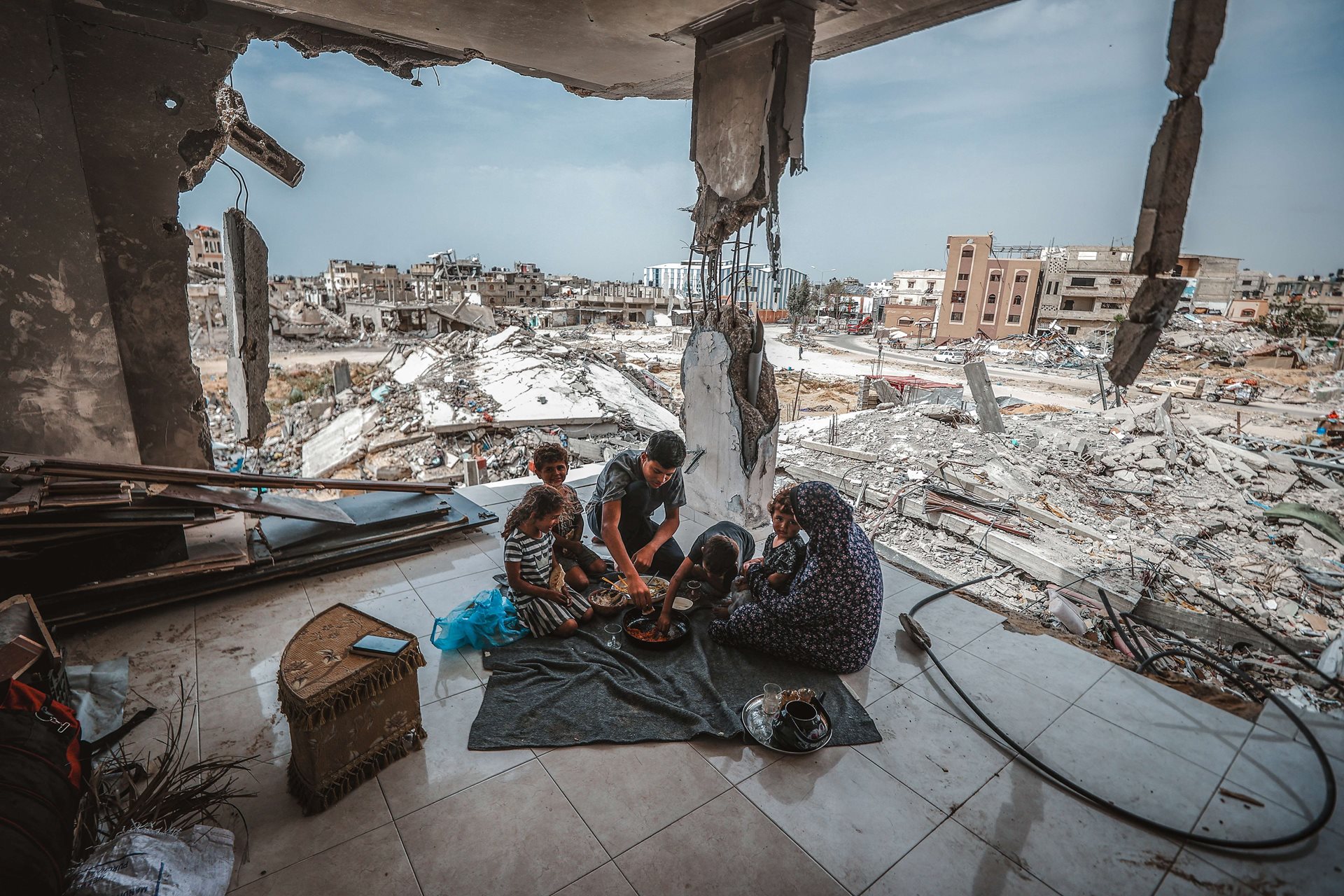 A family takes a meal in the ruins of their old home, &nbsp;in Khan Younis, Gaza, two weeks after an Israeli withdrawal from the city. Citizens returning to the ruined city were trying to recover something of daily life. However, further Israeli incursions to the city occurred later in the year, and continued into 2025.