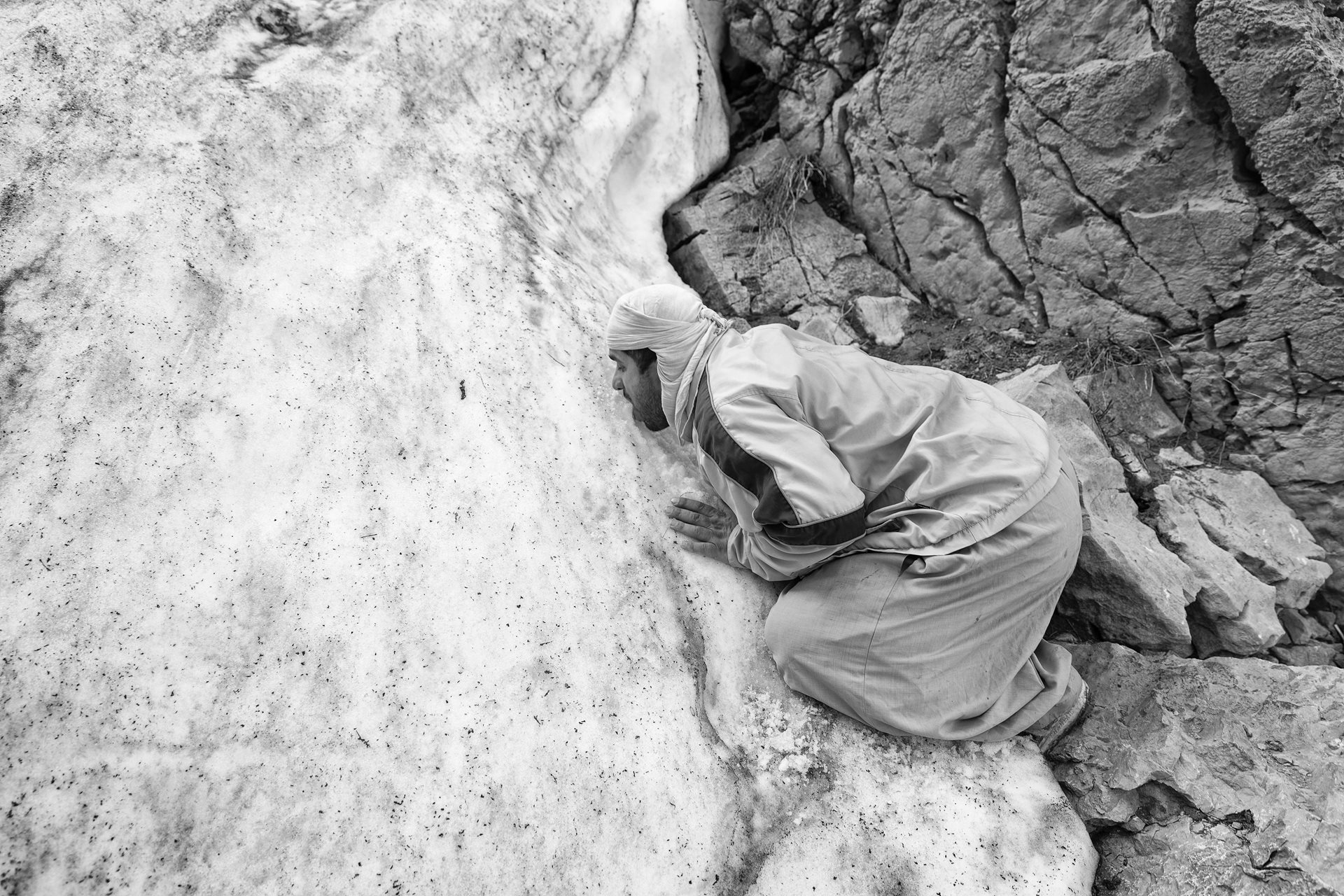 A kolbar pauses to eat snow along a kolbari path, in Kurdistan, Iran/Iraq. Unable to carry extra provisions on their demanding journey, kolbars rely on snow or spring water to quench their thirst. Kurdistan.