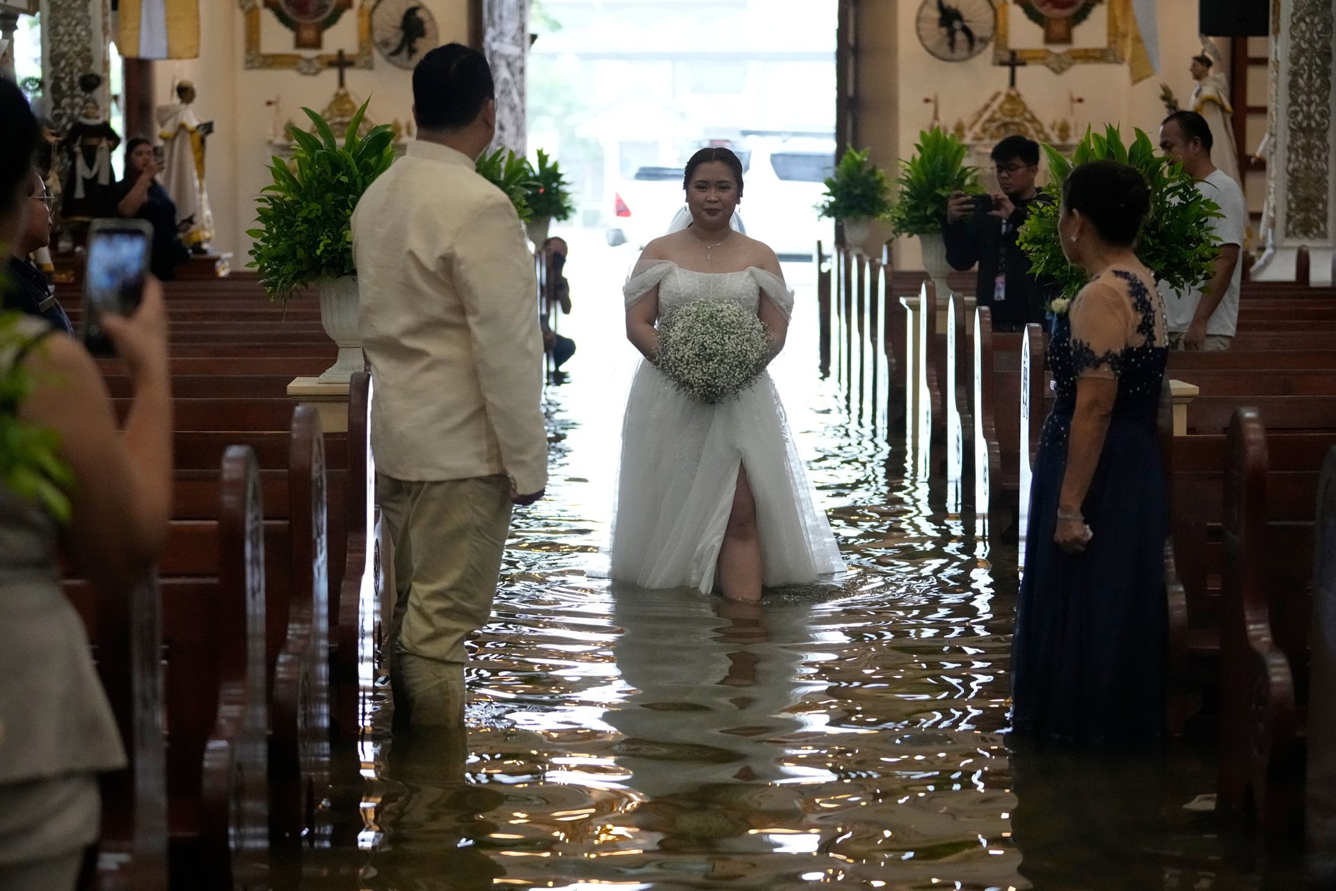 Bride Jamaica Aguilar walks down the flooded aisle of the Barasoain Church in Malolos, Bulacan province, Philippines. The night before the ceremony, the bride remained uncertain about whether to proceed, as wedding planners warned that Typhoon Wipha was intensifying the monsoon rains.