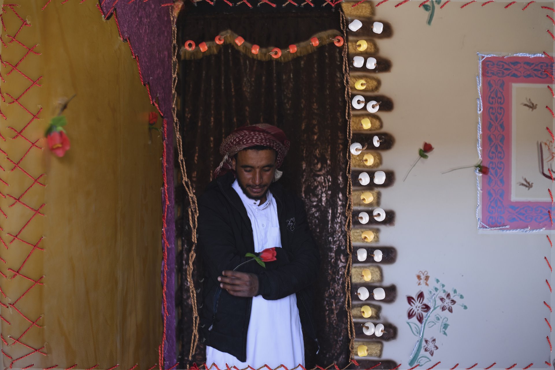 <p>Mahmoud stands in his home in Al-Tarfa village, South Sinai, Egypt. Nora, Mahmoud&rsquo;s cousin, embroidered his portrait.</p>
