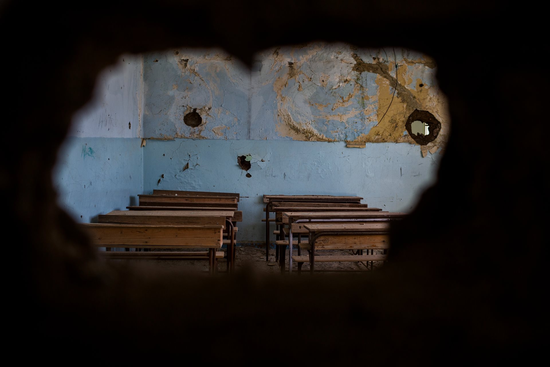 A destroyed classroom seen through a hole in a wall at Tell Ruman school in Al-Hasakah, Syria, closed since ISIS attacked it in July 2015.