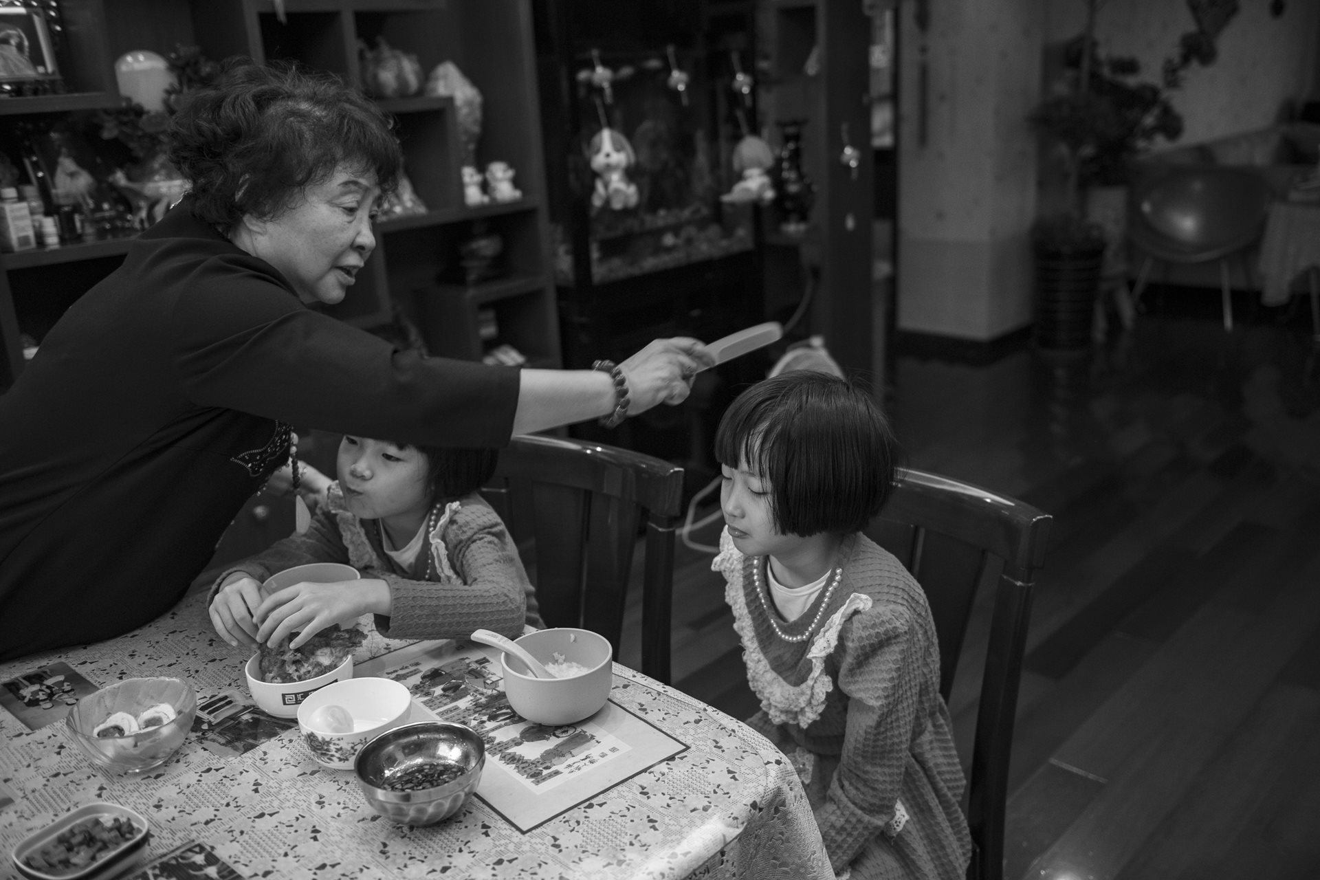 Sheng Hailin combs her daughters' hair before school. This daily routine illustrates what the photographer describes as a "race against time"&mdash;a mother maintaining her physical capacity to care for growing children. Hefei, Anhui Province, China.