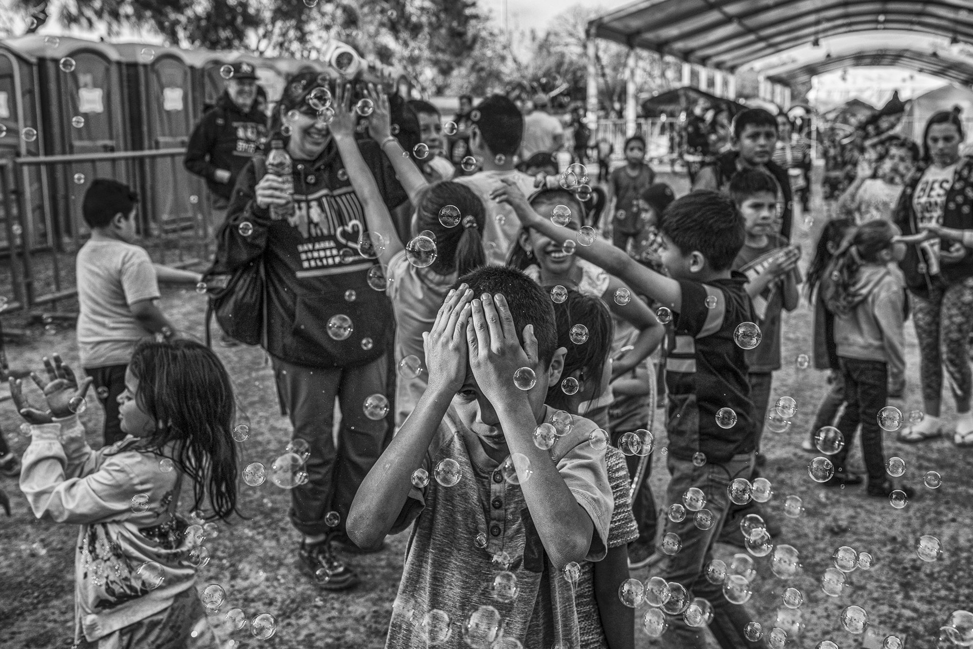 A migrant child covers his face from bubbles at a game session for kids organized by a NGO at a migrant and asylum seeker camp in Matamoros, Mexico.&nbsp;