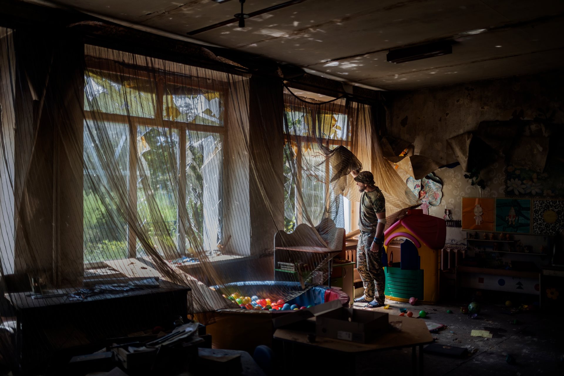 A Ukrainian soldier from the Ares battalion, 129th Territorial Defense Brigade, gazes out of a kindergarten window at the southern front in the Donetsk region, Ukraine.
