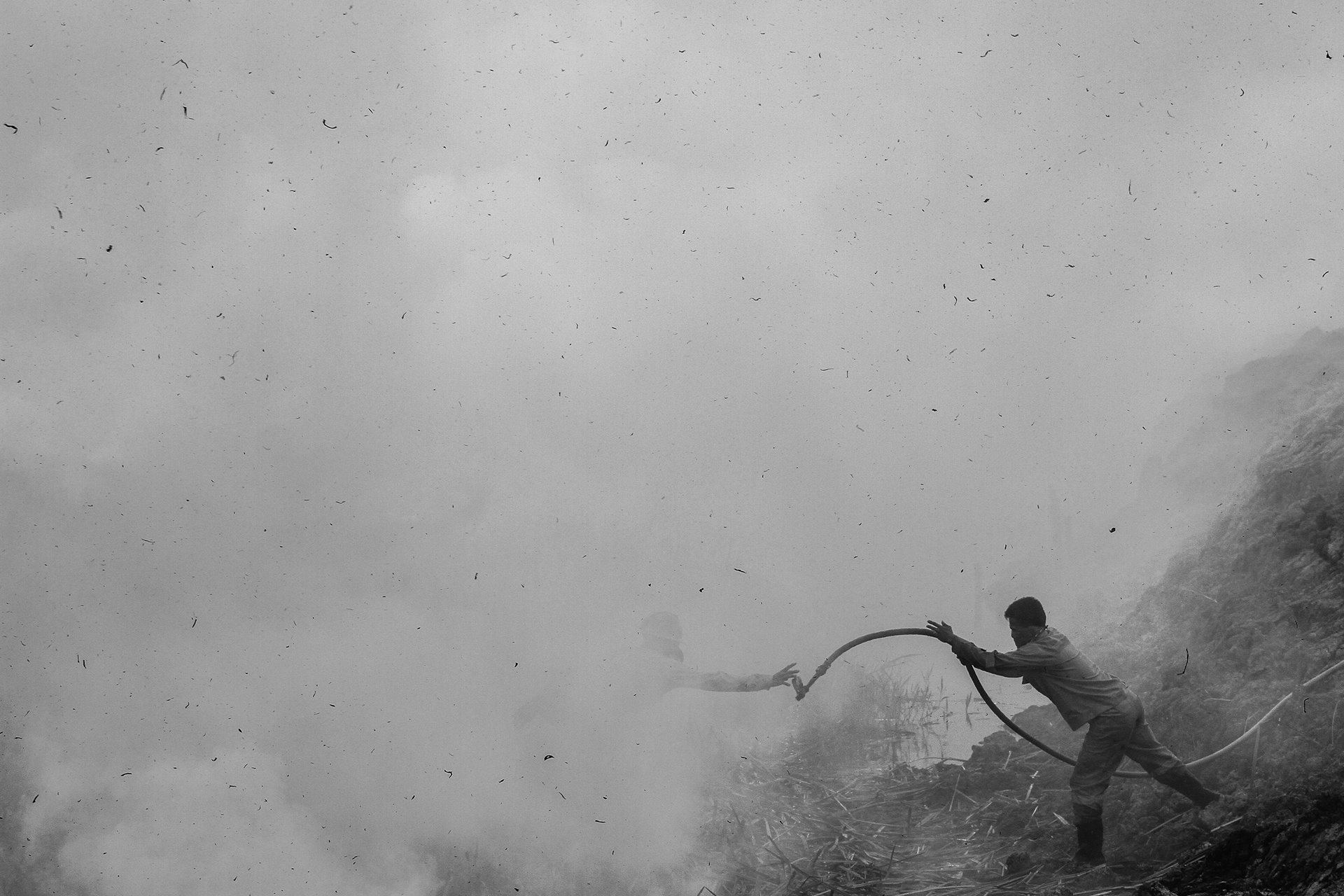 A firefighter throws another a hose, while attempting to extinguish a fire in Ogan Ilir, South Sumatra.