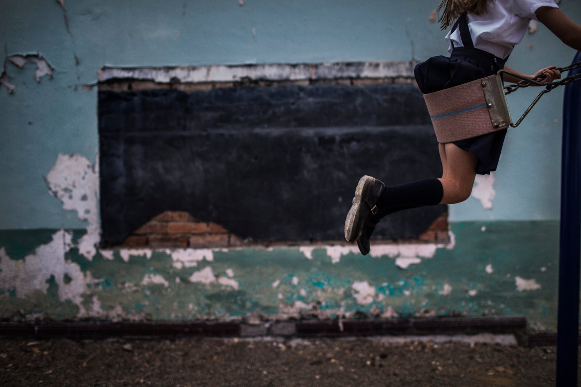 A girl on a swing in the playground of a school in El Tambo, Cauca, Colombia, located directly across from a police station. Students have been caught in violent clashes between armed groups and police for decades. The school was severely damaged by cylinder bombs in 2012.