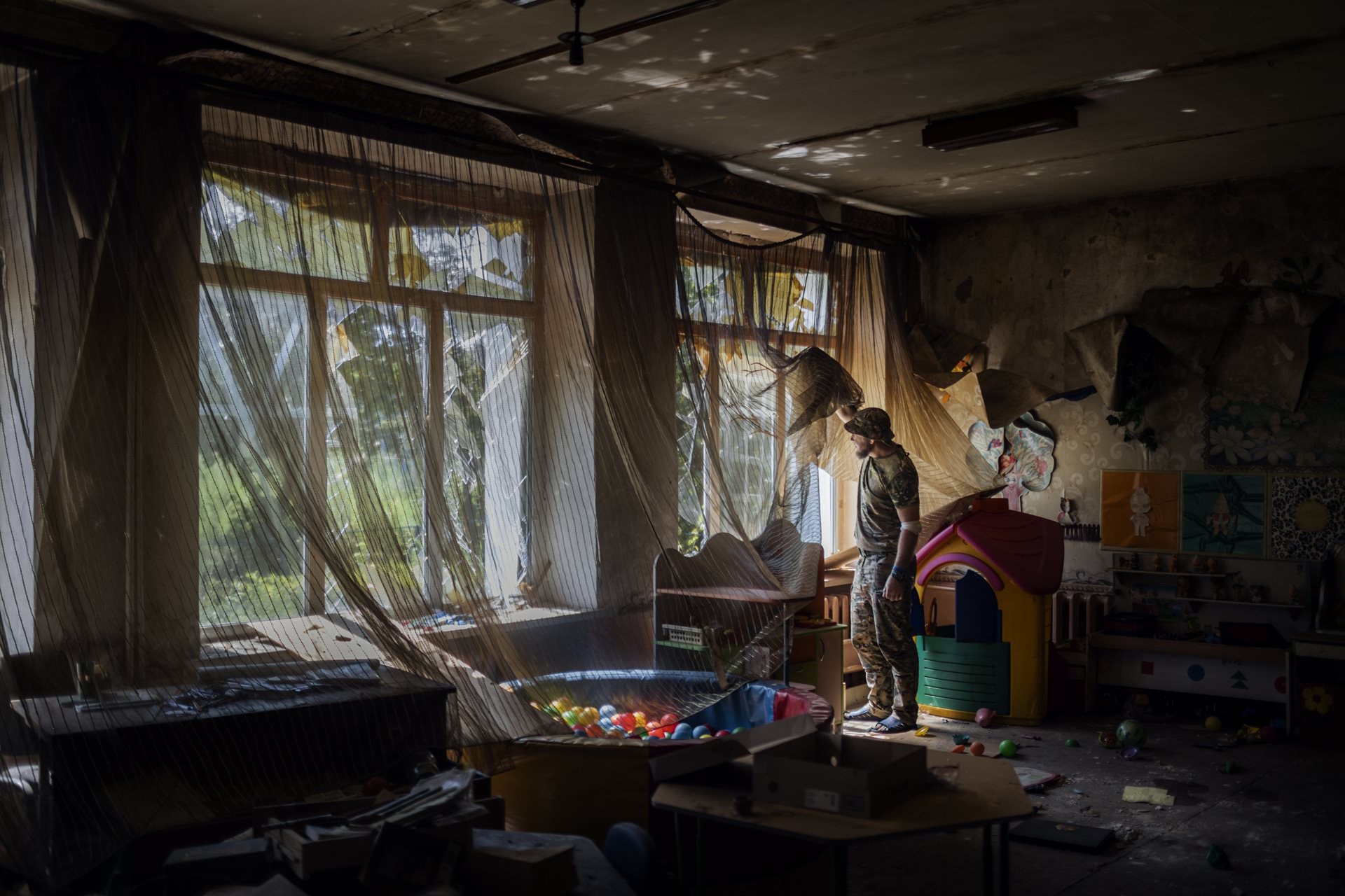 A Ukrainian soldier from the Ares battalion, 129th Territorial Defense Brigade, gazes out of a kindergarten window at the southern front, in Donetsk region, Ukraine.